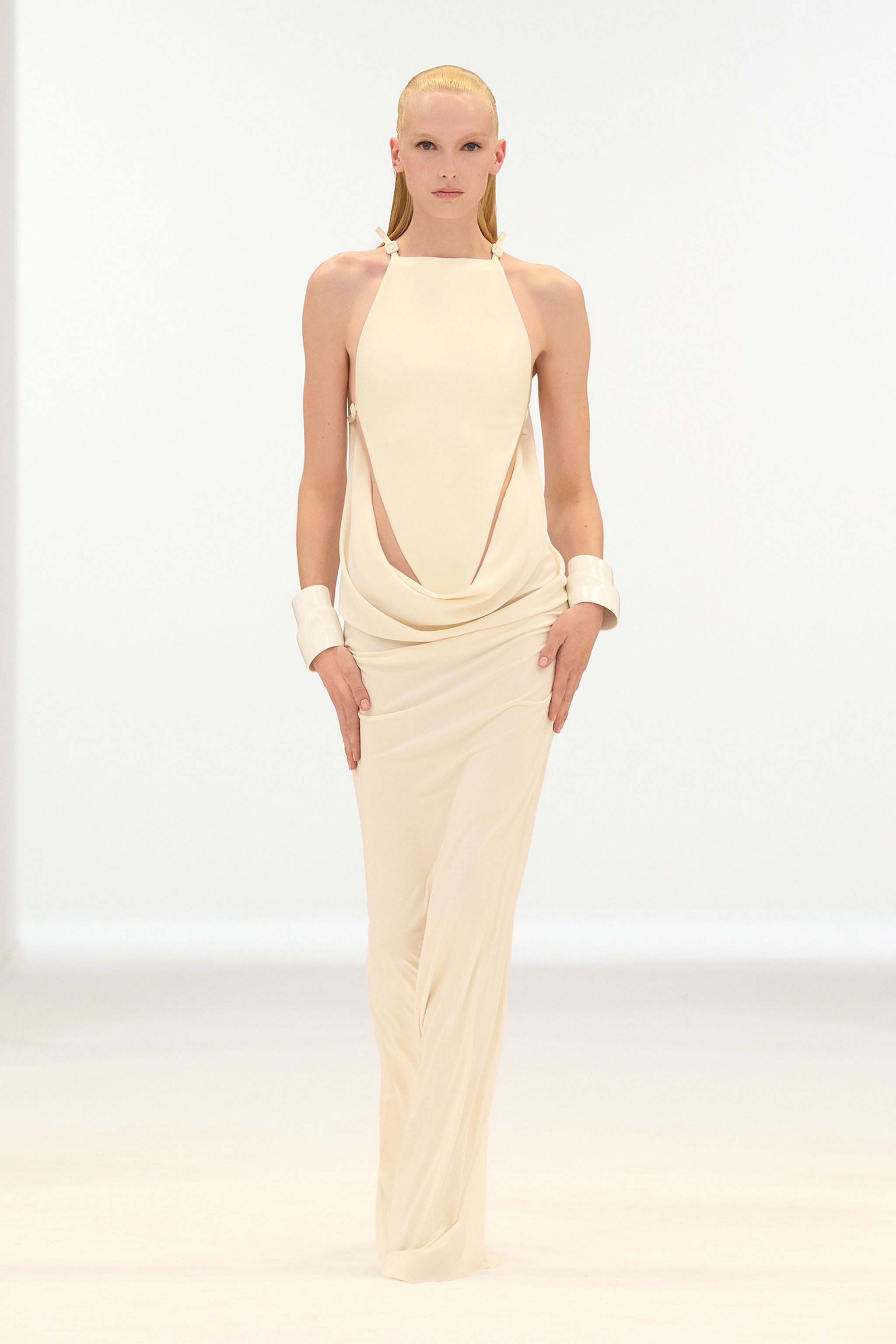 Elegant ivory dress with cutouts, showcased on a model for Courrèges fashion website.