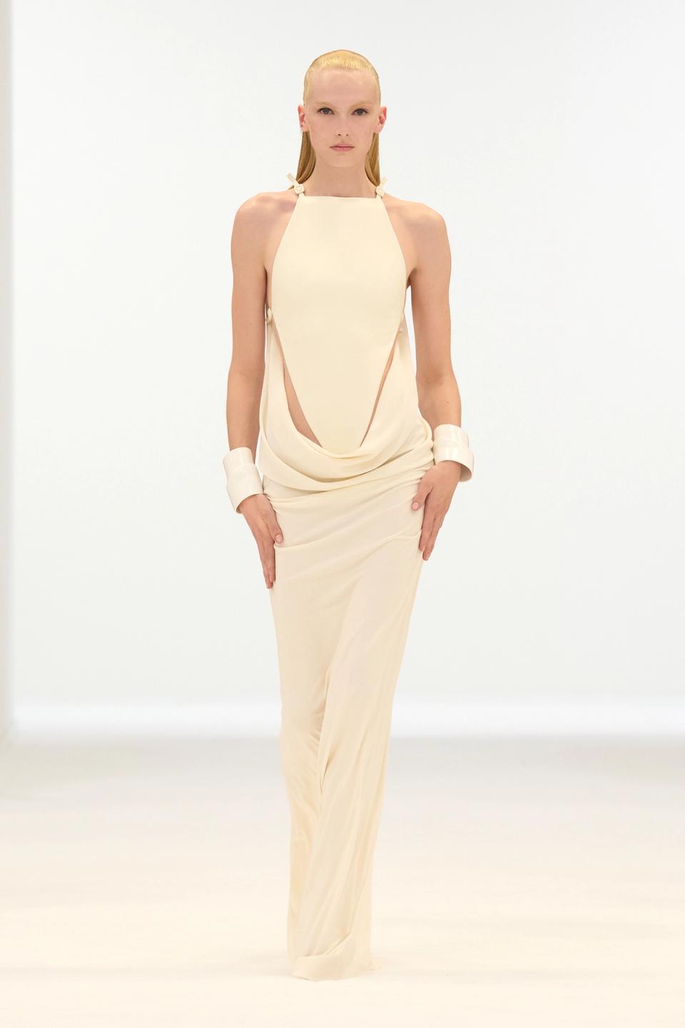 Elegant ivory dress with cutouts, showcased on a model for Courrèges fashion website.