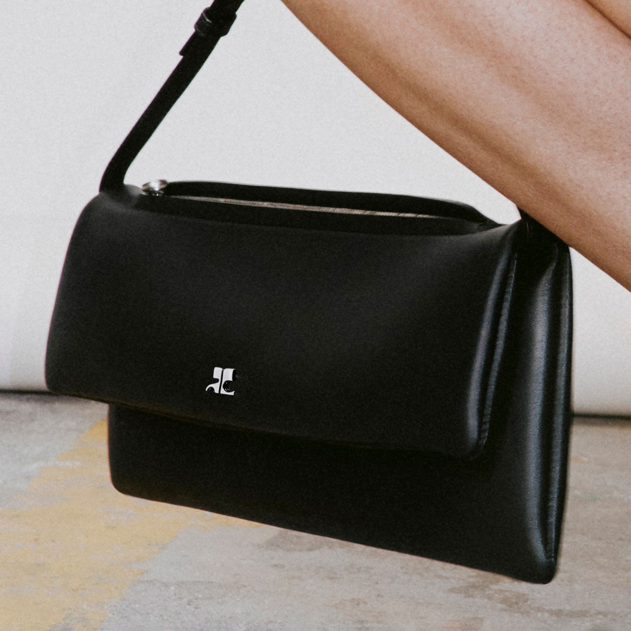 Elegant black Courrèges handbag showcased on an ecommerce site for the fashion brand.