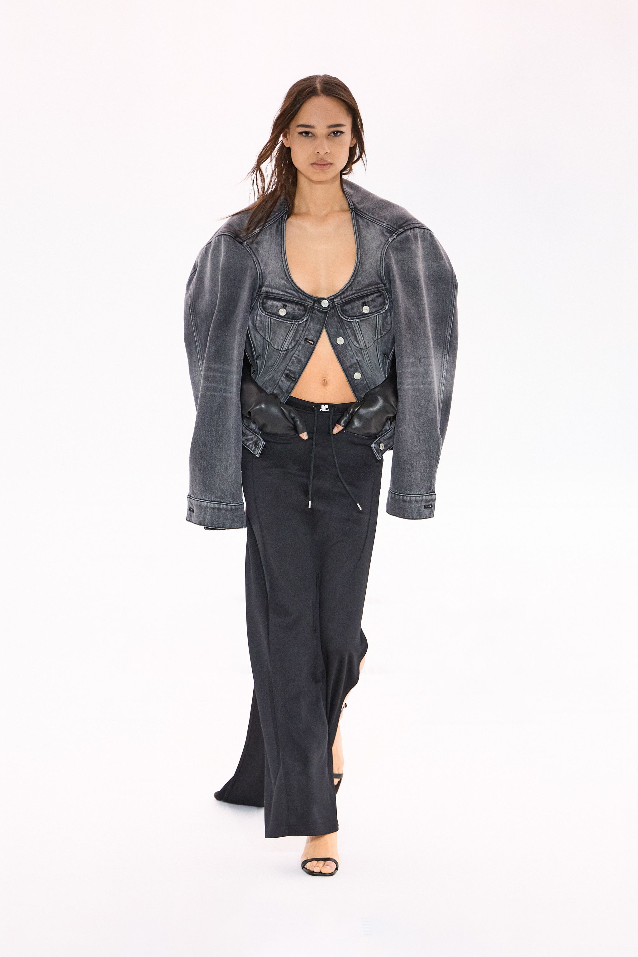 Elegant black denim cropped jacket with shoulder padding, paired with black relaxed trousers for Courrèges.