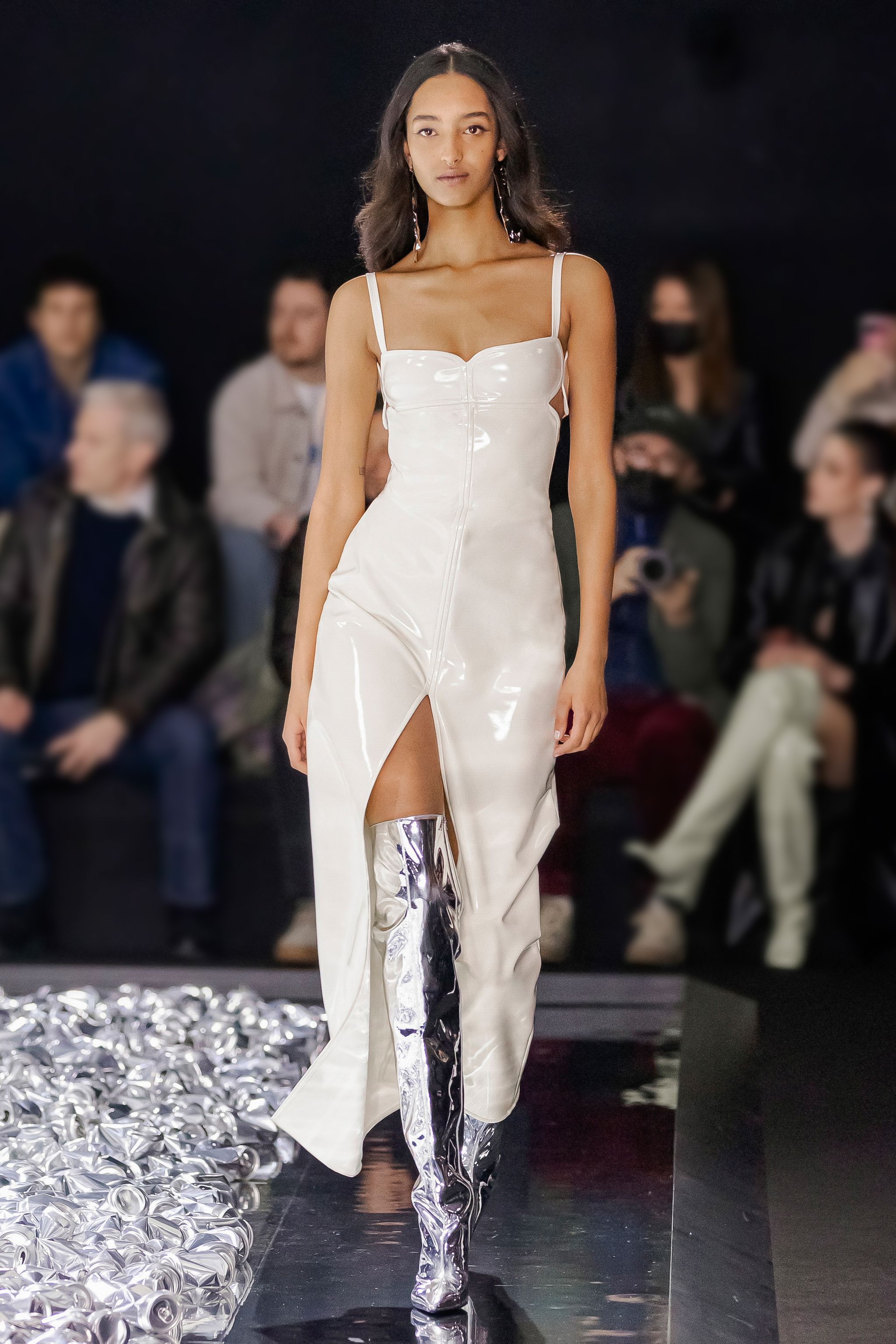 Elegant model walking on runway in white dress with silver knee-high boots for Courrèges.