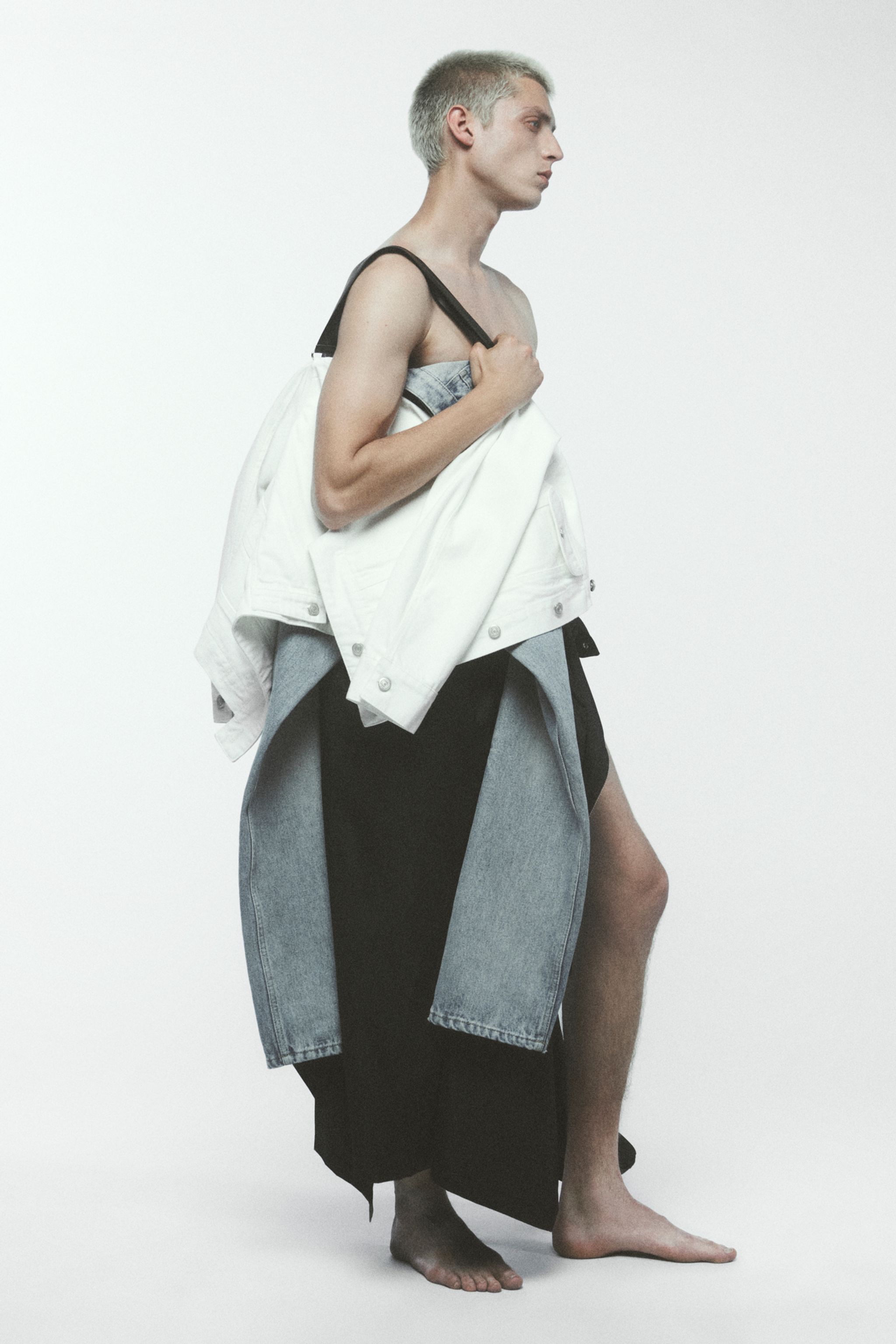 Elegant modern fashion look featuring denim, white jacket, and layered black and gray garments for Courrèges.