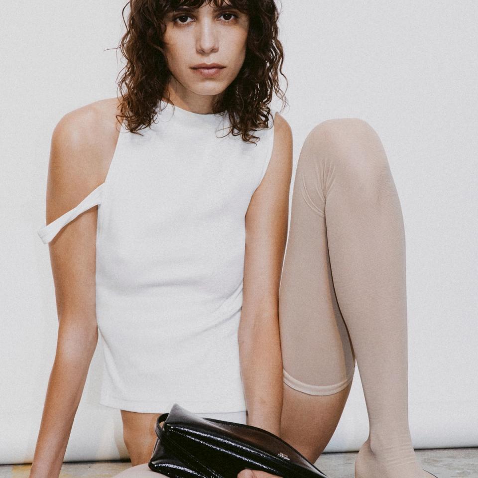 Elegant Courrèges fashion model with beige tights and a white top for an ecommerce website.