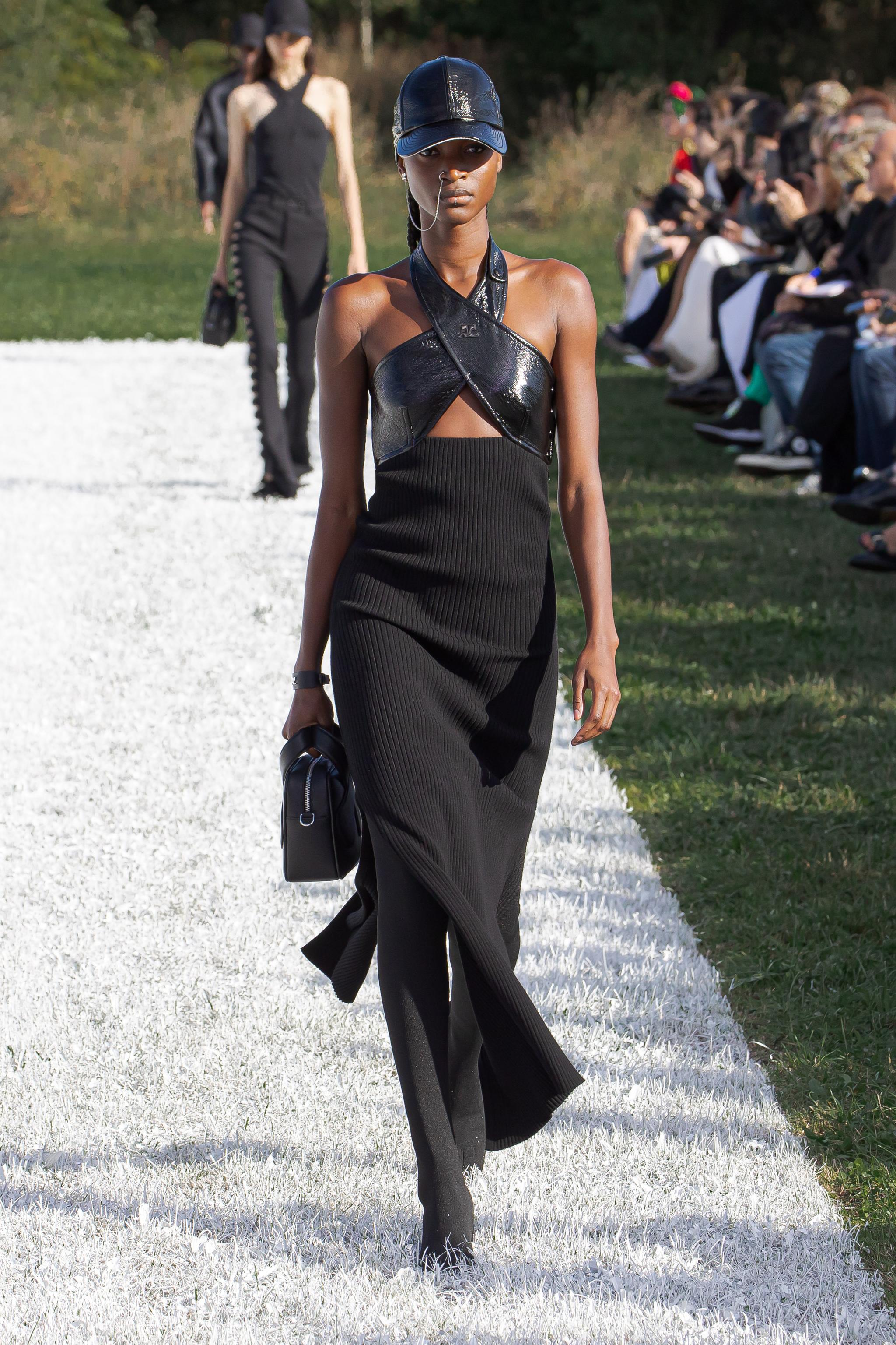 Elegant black dress with leather accents, worn on a runway during a Courrèges fashion show.