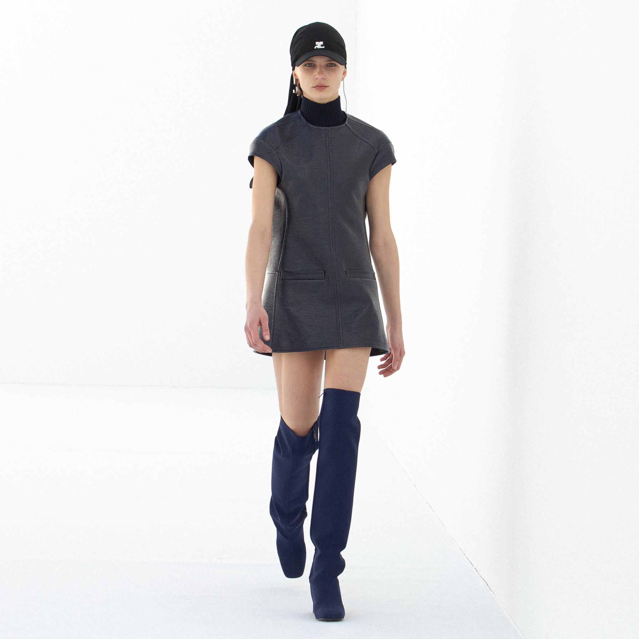 Robe courte noire élégante de Courrèges avec des bottes hautes, présentée sur un mannequin.