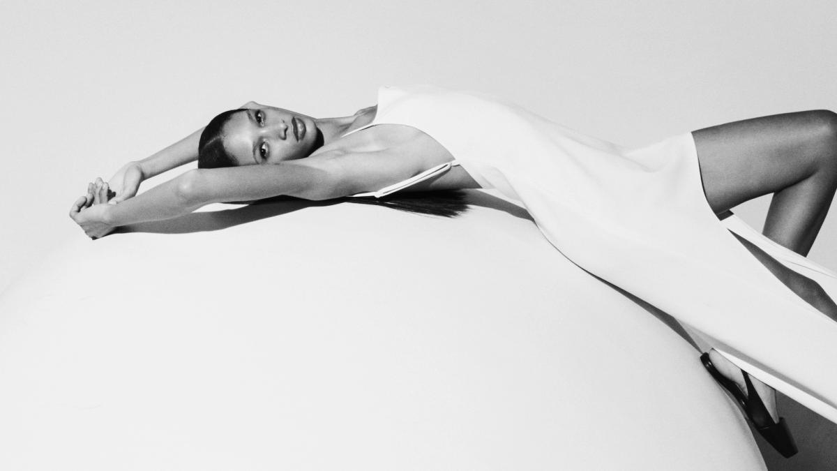 Elegant black-and-white image of a model lying down in modern fashion for Courrèges.