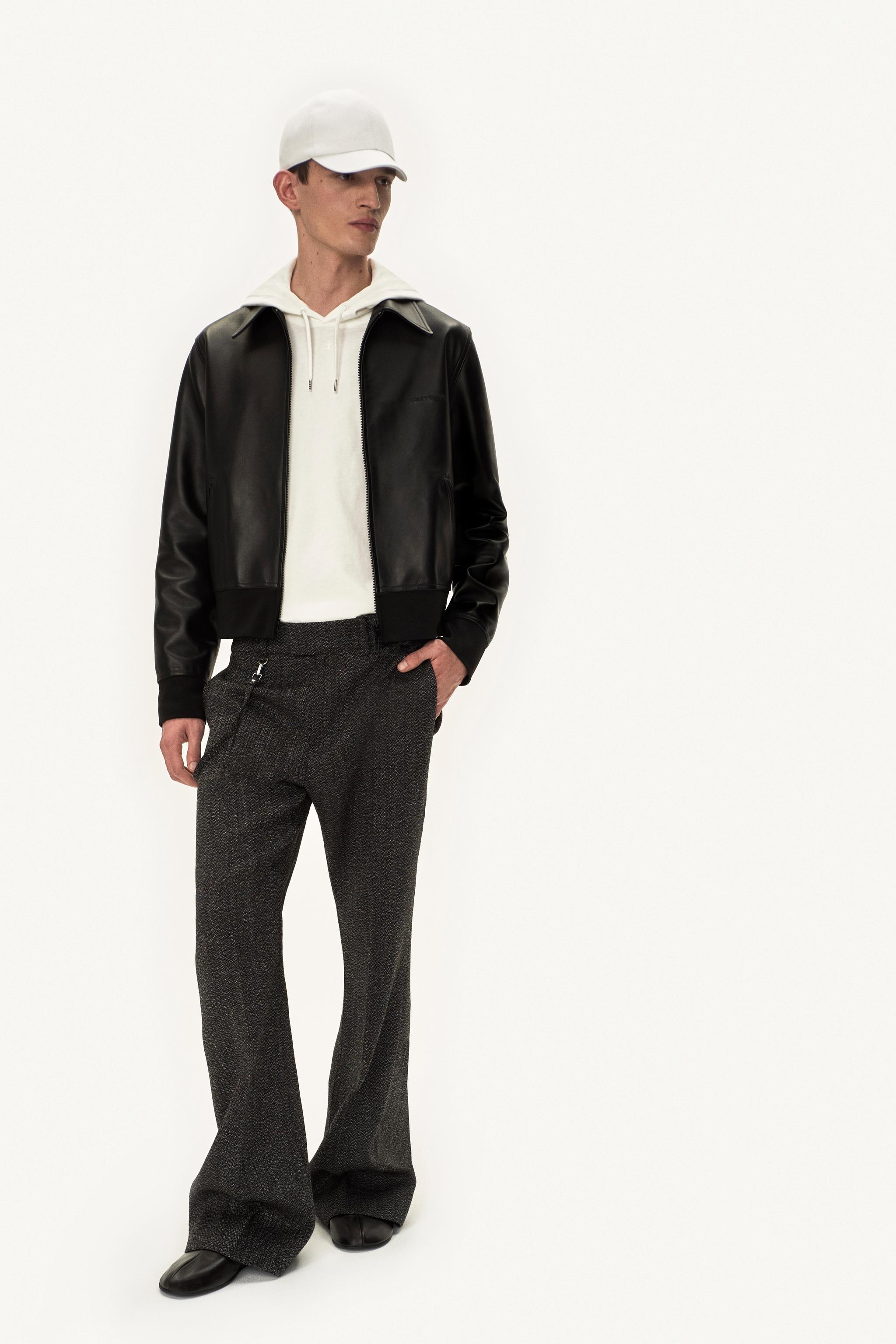 Tenue élégante pour homme avec une veste en cuir noir, sweat blanc et pantalon large pour Courrèges.