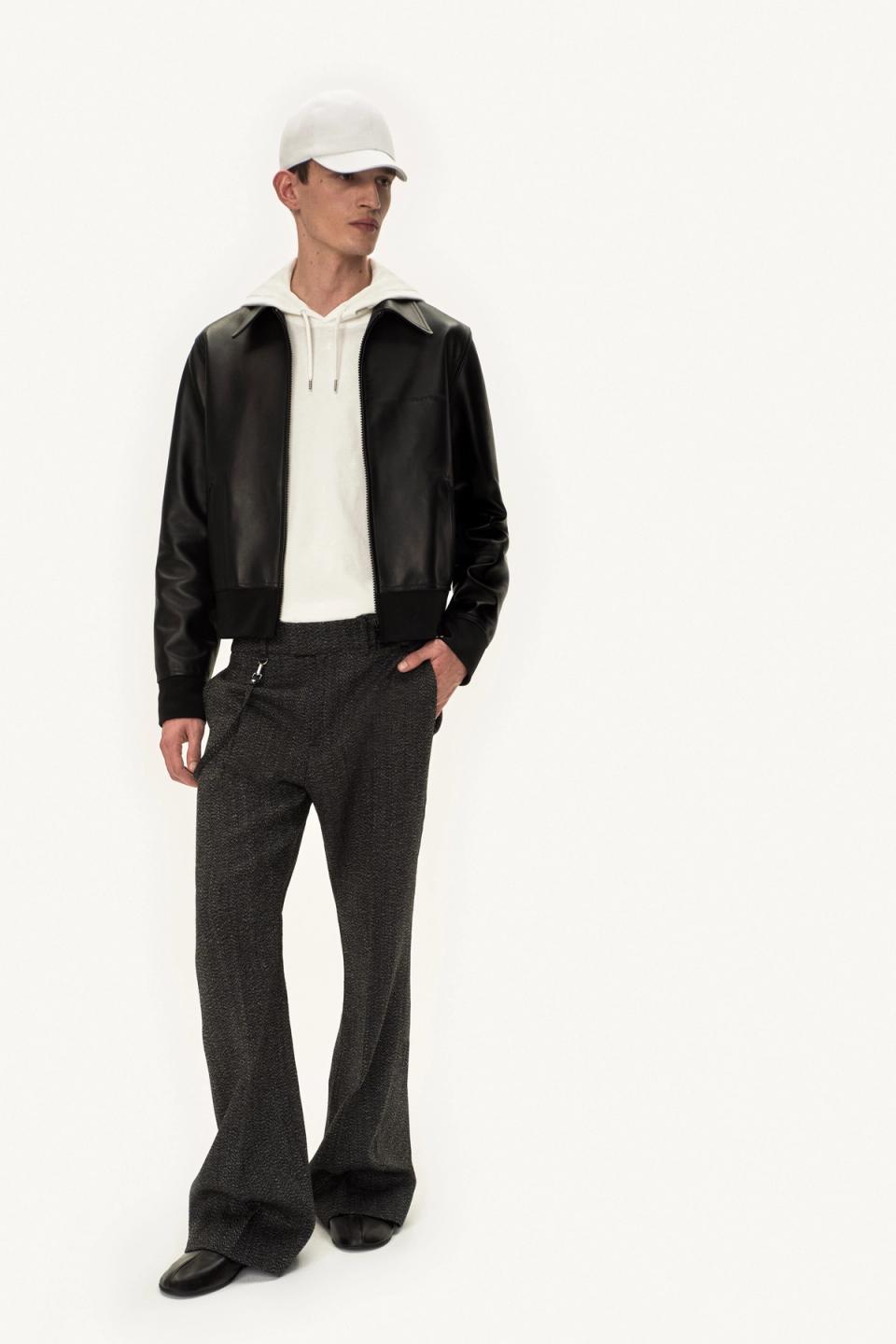Elegant men's fashion look featuring a leather jacket, hoodie, and tailored trousers for Courrèges.
