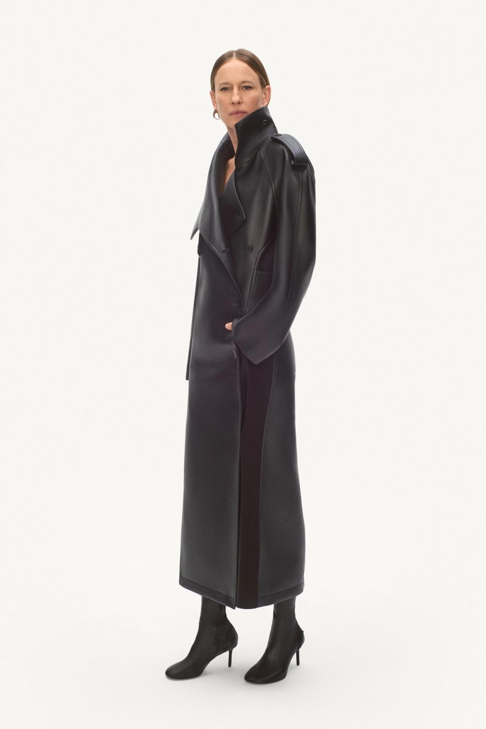 Elegant woman in a black leather trench coat and high-heeled boots, showcasing Courrèges fashion.