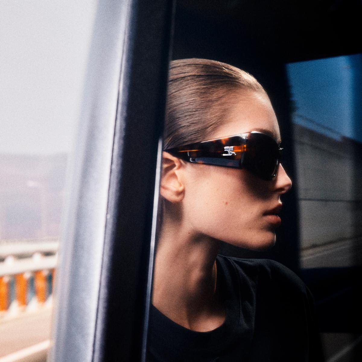 Elegant woman with slicked-back hair wearing stylish sunglasses for Courrèges fashion.