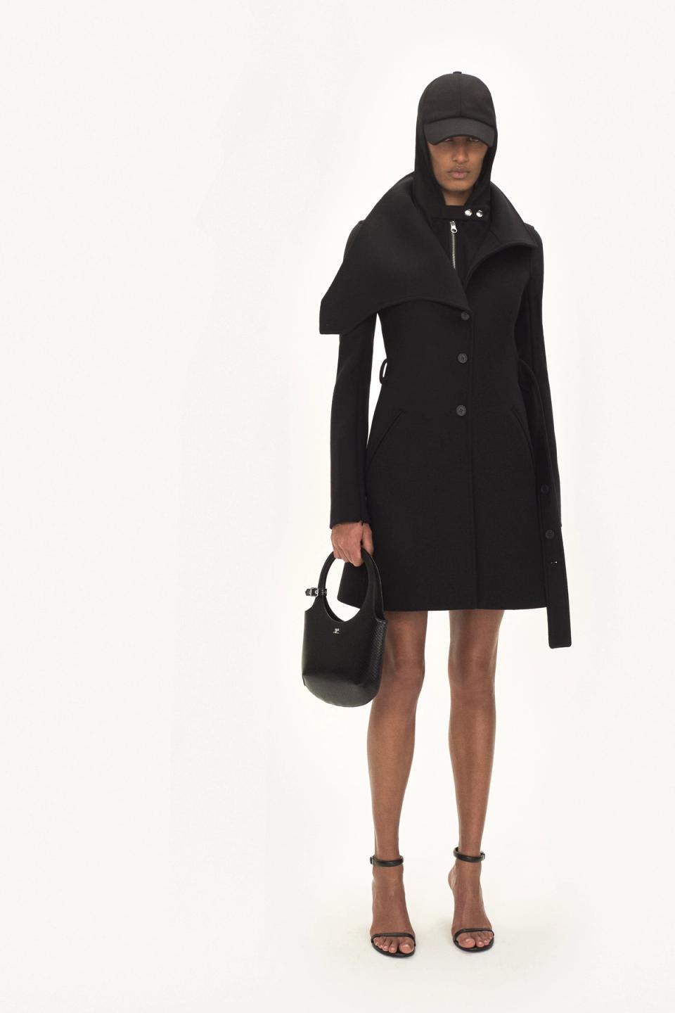 Elegant black coat with oversized collar, stylish handbag, and heels showcasing Courrèges fashion.