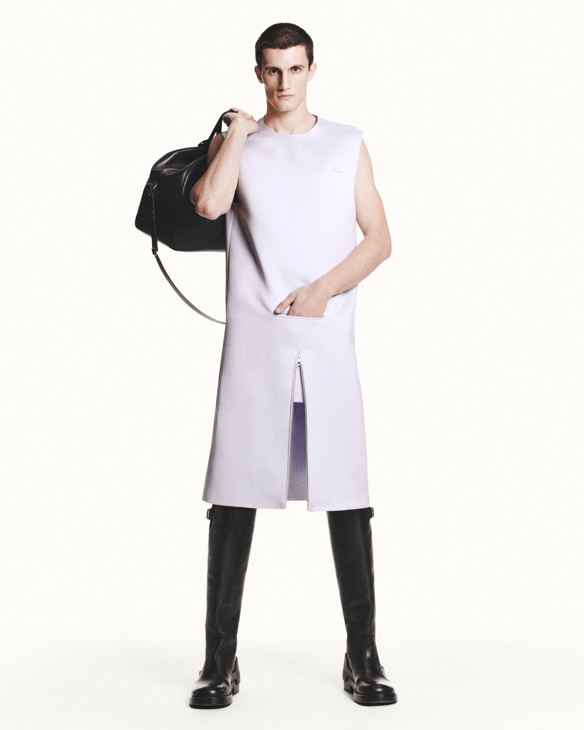 Elegant model in white fashion dress with zipper detail, carrying a black bag, for Courrèges website.