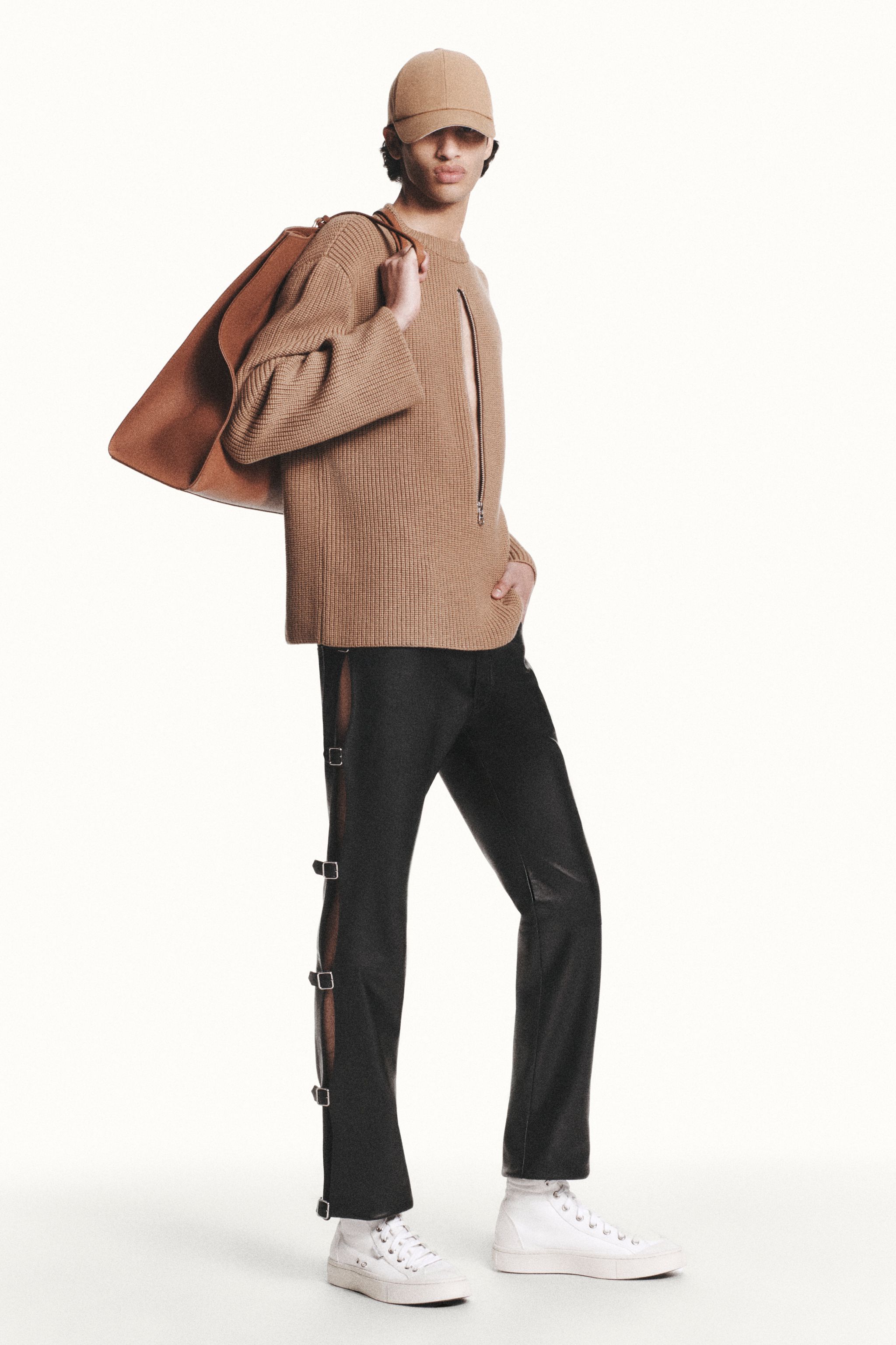 Elegant casual outfit for Courrèges fashion, featuring a beige knit top, black pants, and white sneakers.