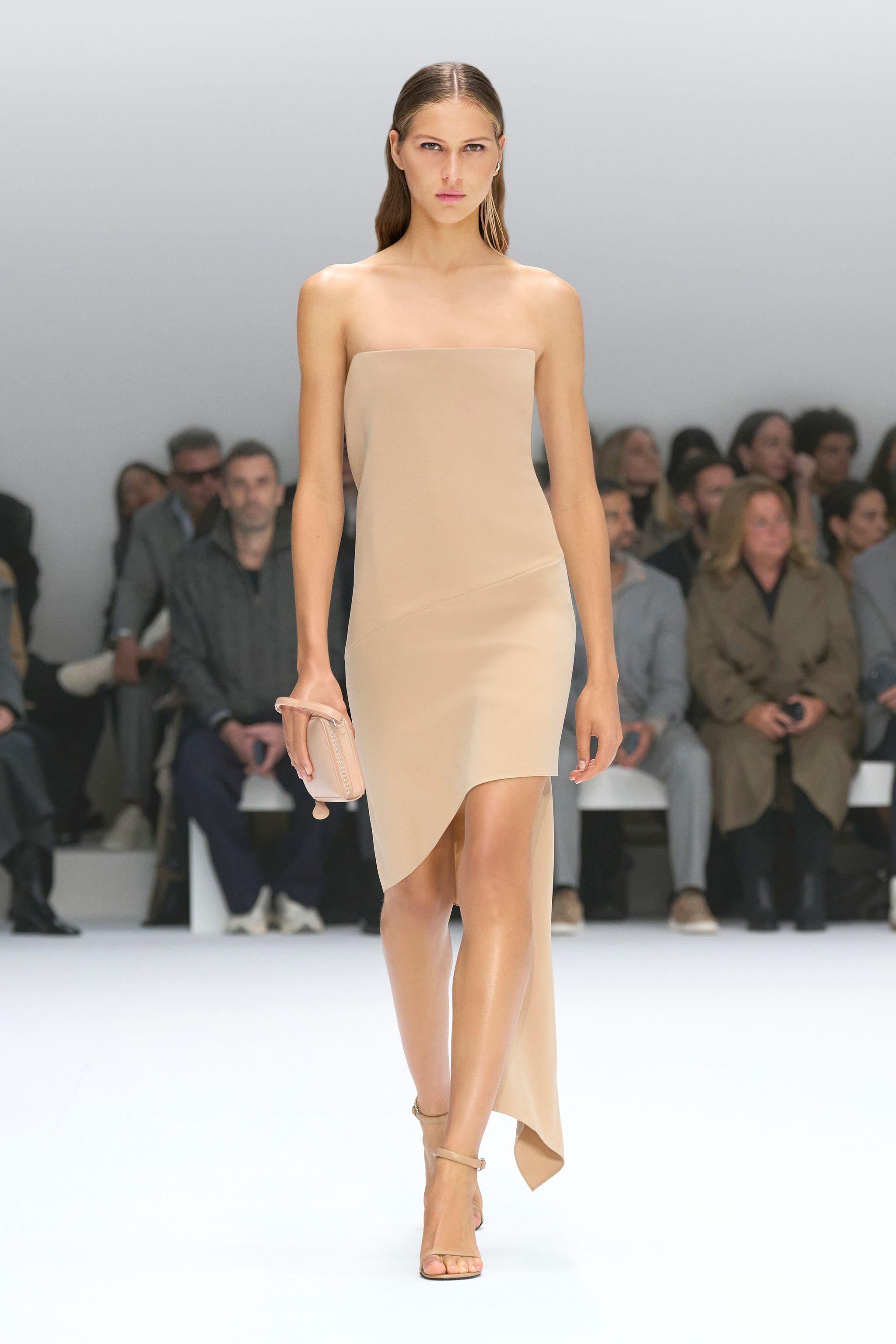 Elegant model wearing a beige strapless dress on Courrèges fashion runway, showcasing chic style.