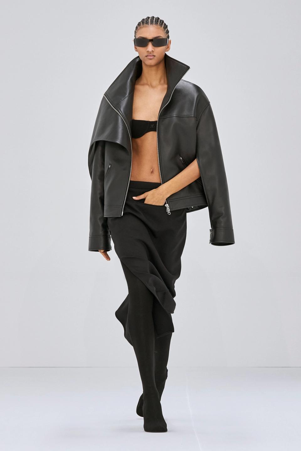 Elegant model in black leather jacket, sunglasses, and stylish black outfit for Courrèges fashion.