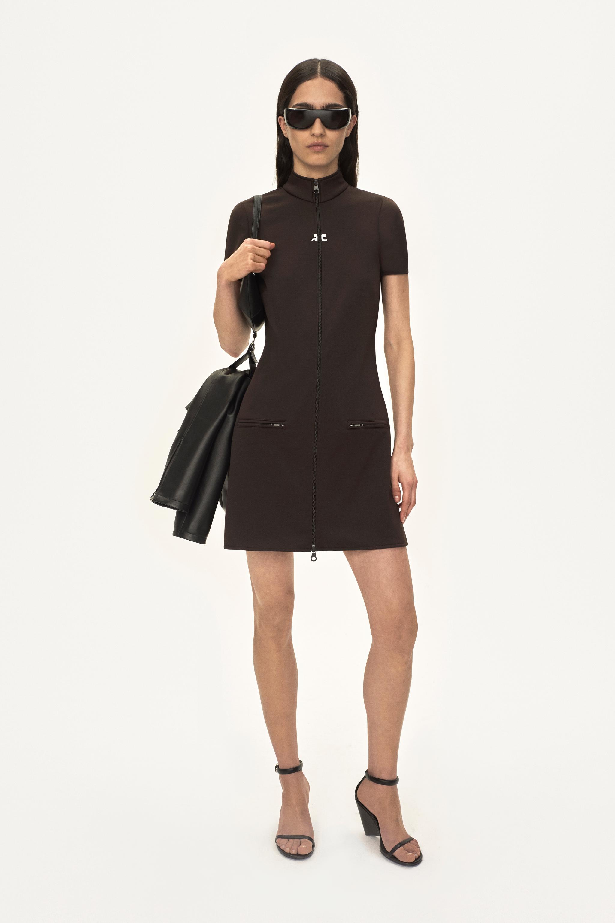 Robe noire chic zippée à col haut, logo Courrèges, avec accessoires tendance pour ecommerce.