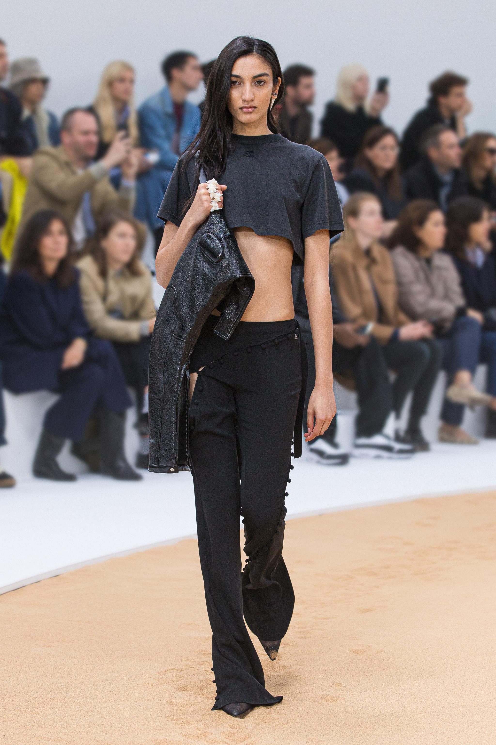 Modèle élégant sur le podium portant un crop top noir et un pantalon noir Courrèges.