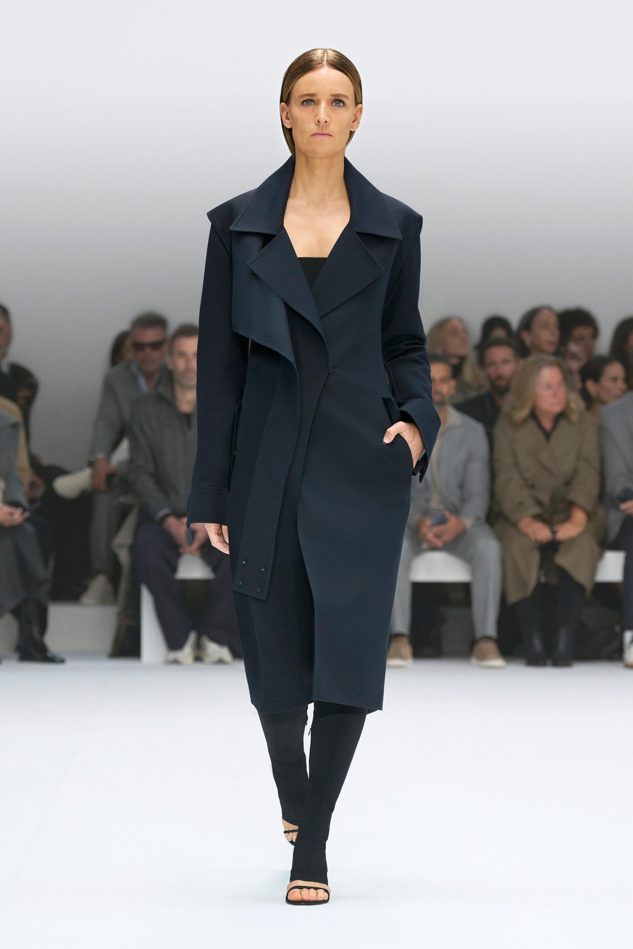 Elegant navy trench coat by Courrèges, showcased on a runway for a sophisticated fashion look.