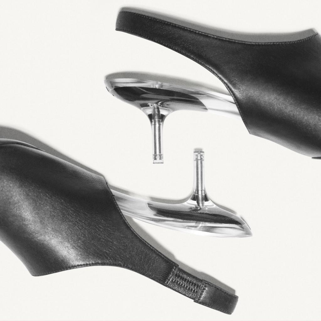 Elegant black leather shoes with clear heels, showcased on an ecommerce site for Courrèges.