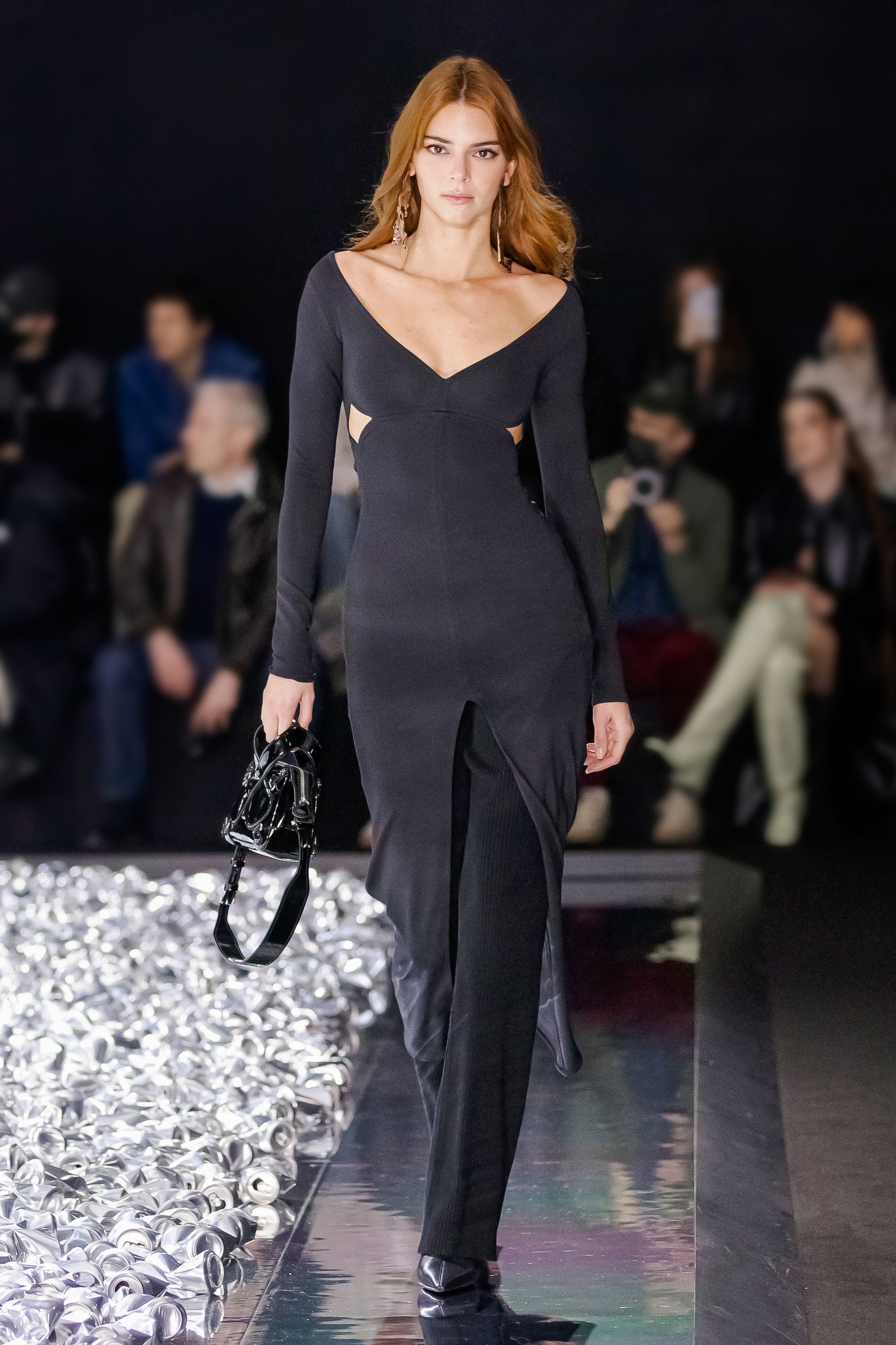 Elegant black dress by Courrèges on a runway with a fashionable audience, showcasing designer style.