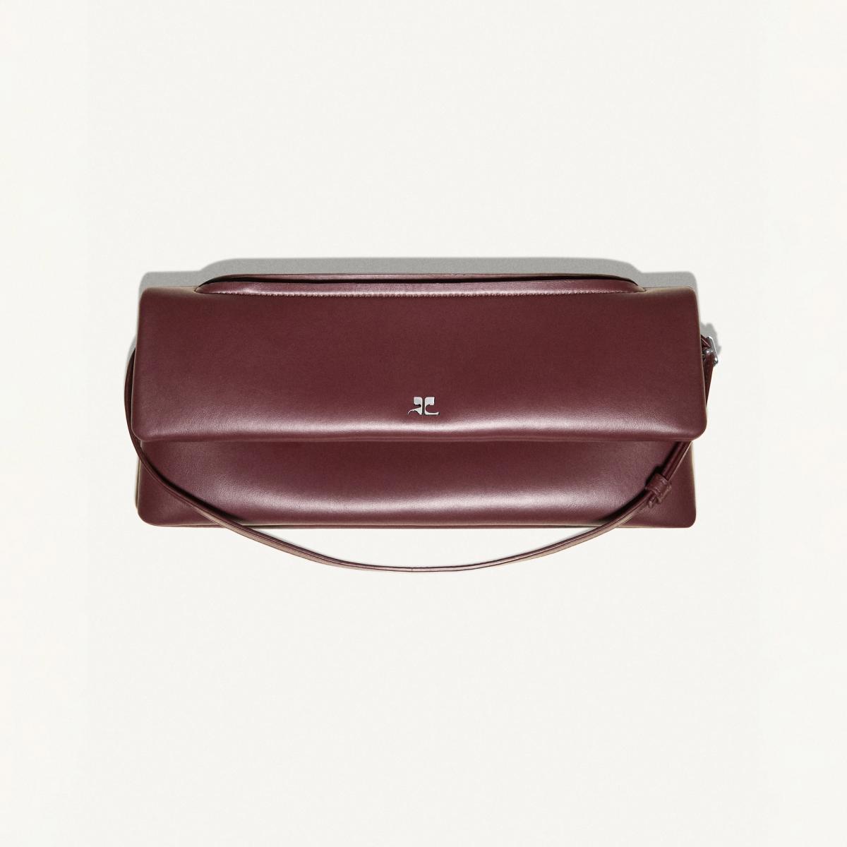 Elegant burgundy leather handbag by Courrèges, showcasing modern minimalist design for fashion lovers.