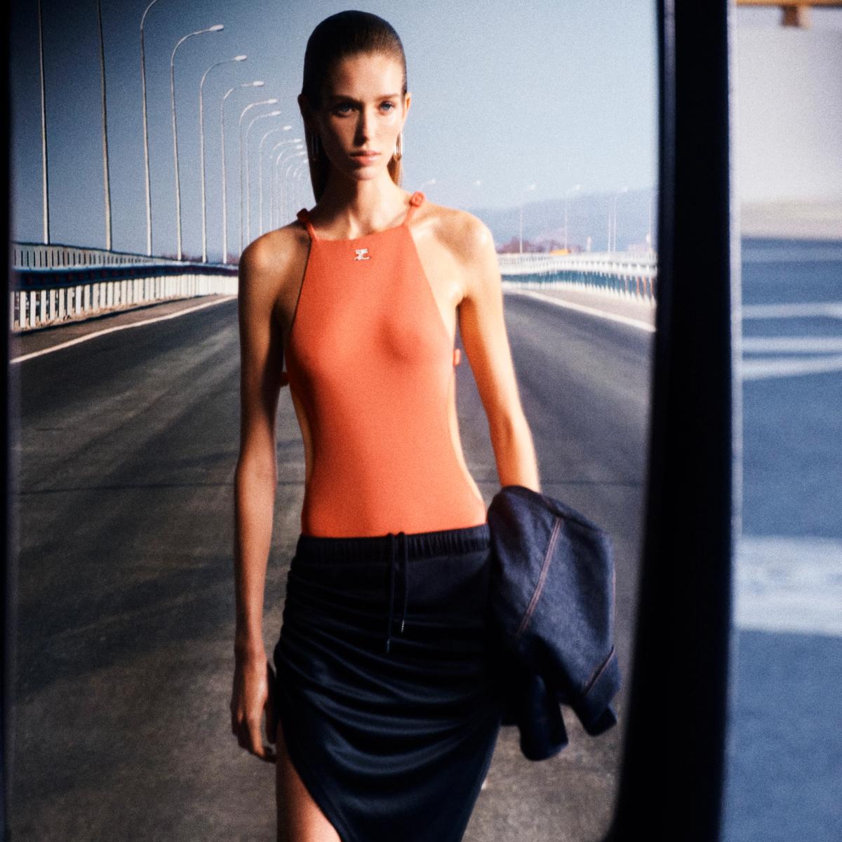 Elegant model showcases Courrèges fashion on a city bridge, highlighting contemporary style.
