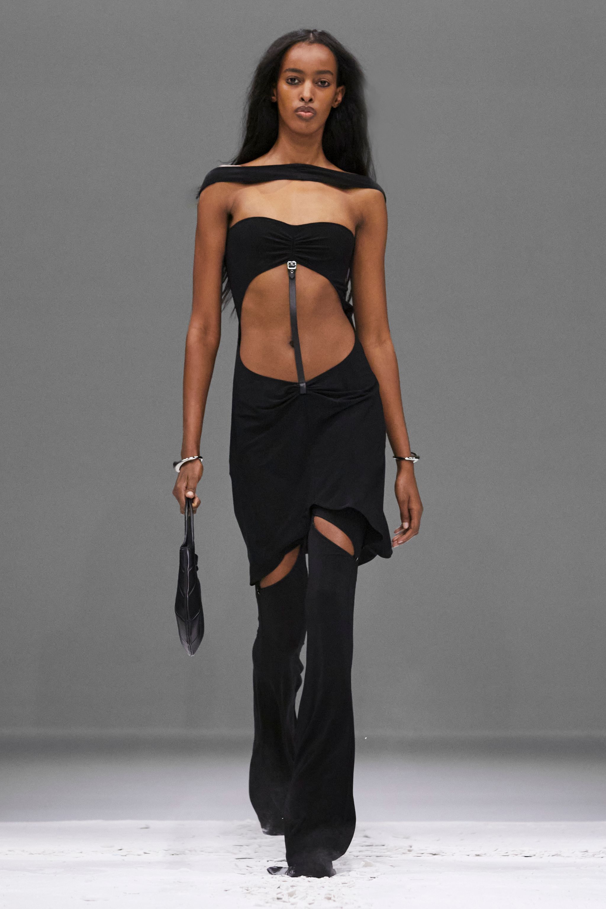 Elegant model in black cutout dress, showcasing Courrèges fashion on runway.