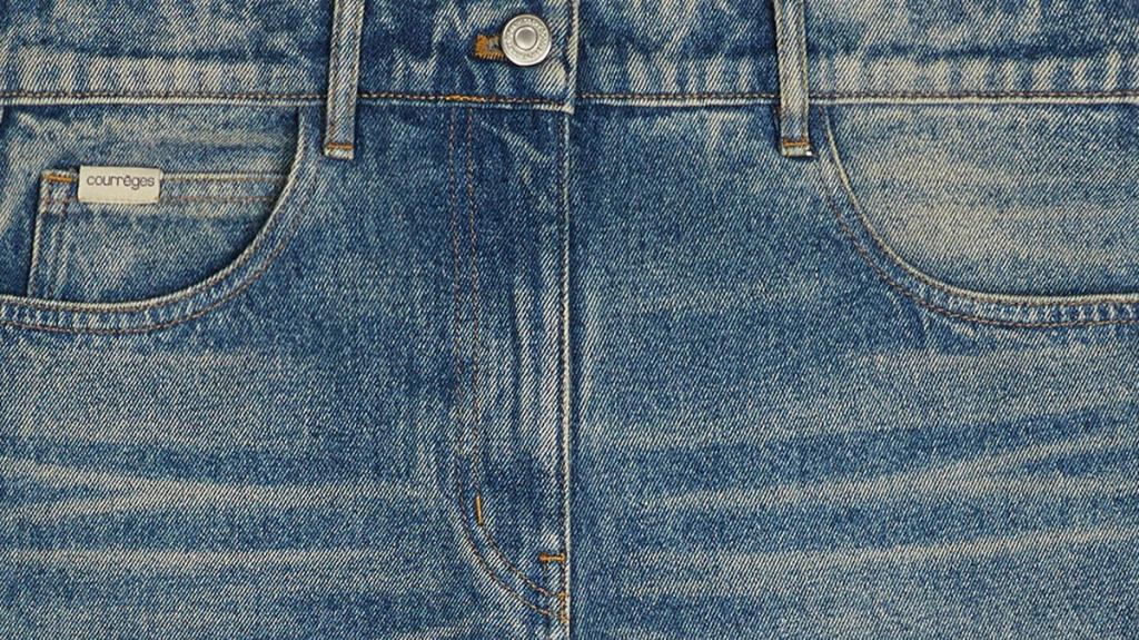 Gros plan sur un jean en denim bleu classique de Courrèges, présentant un style moderne et élégant.