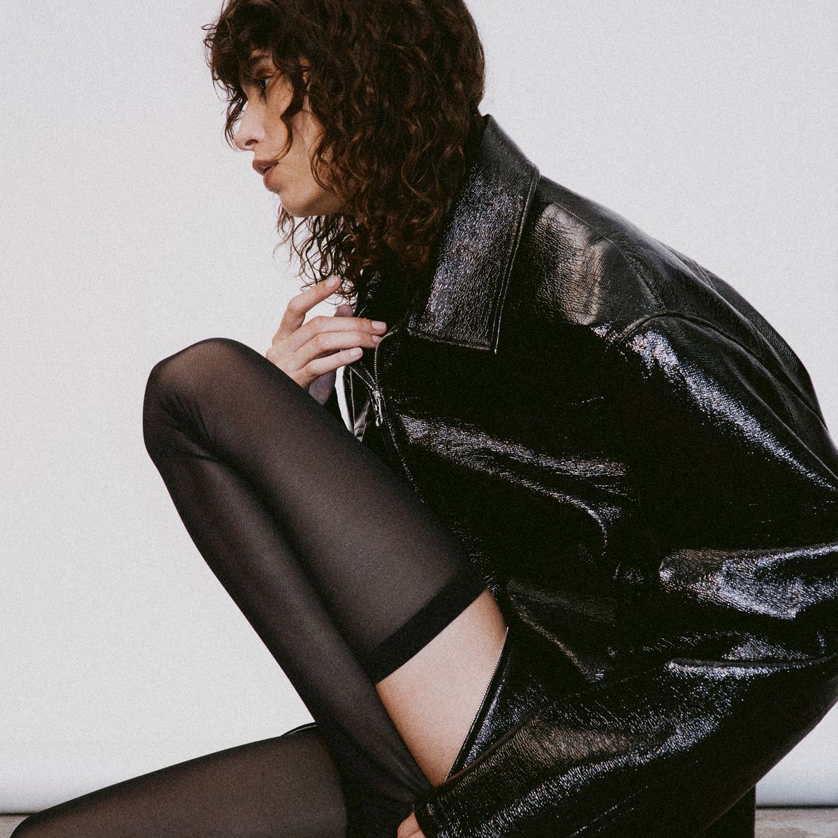 Elegant black leather jacket and sheer tights showcase Courrèges fashion on an ecommerce site.