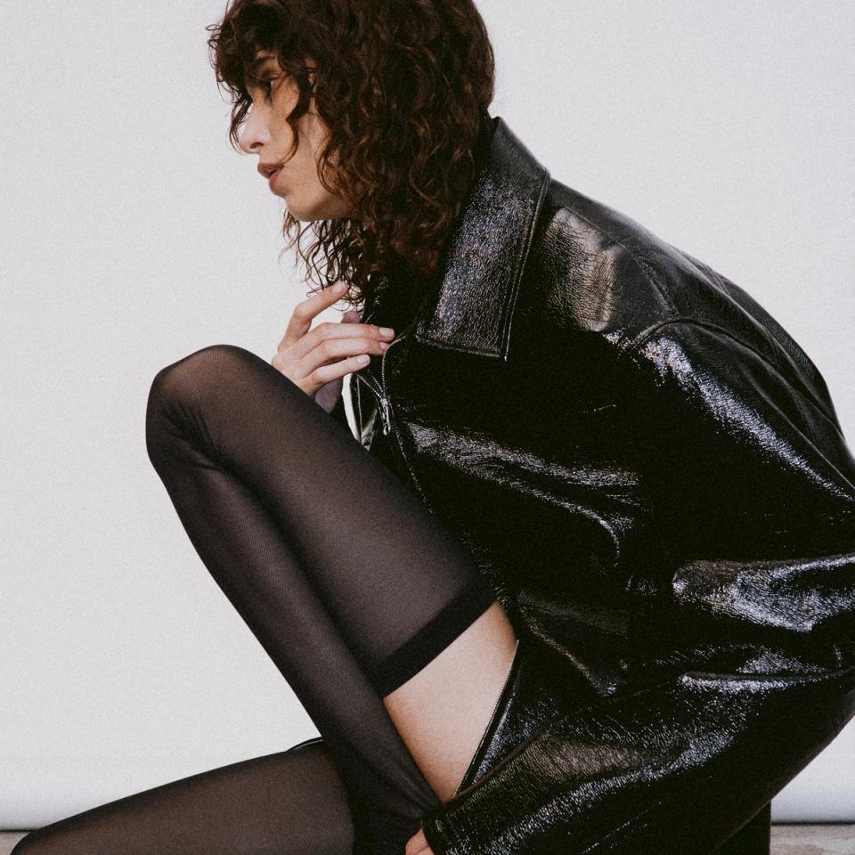 Elegant black leather jacket and sheer tights showcase Courrèges fashion on an ecommerce site.