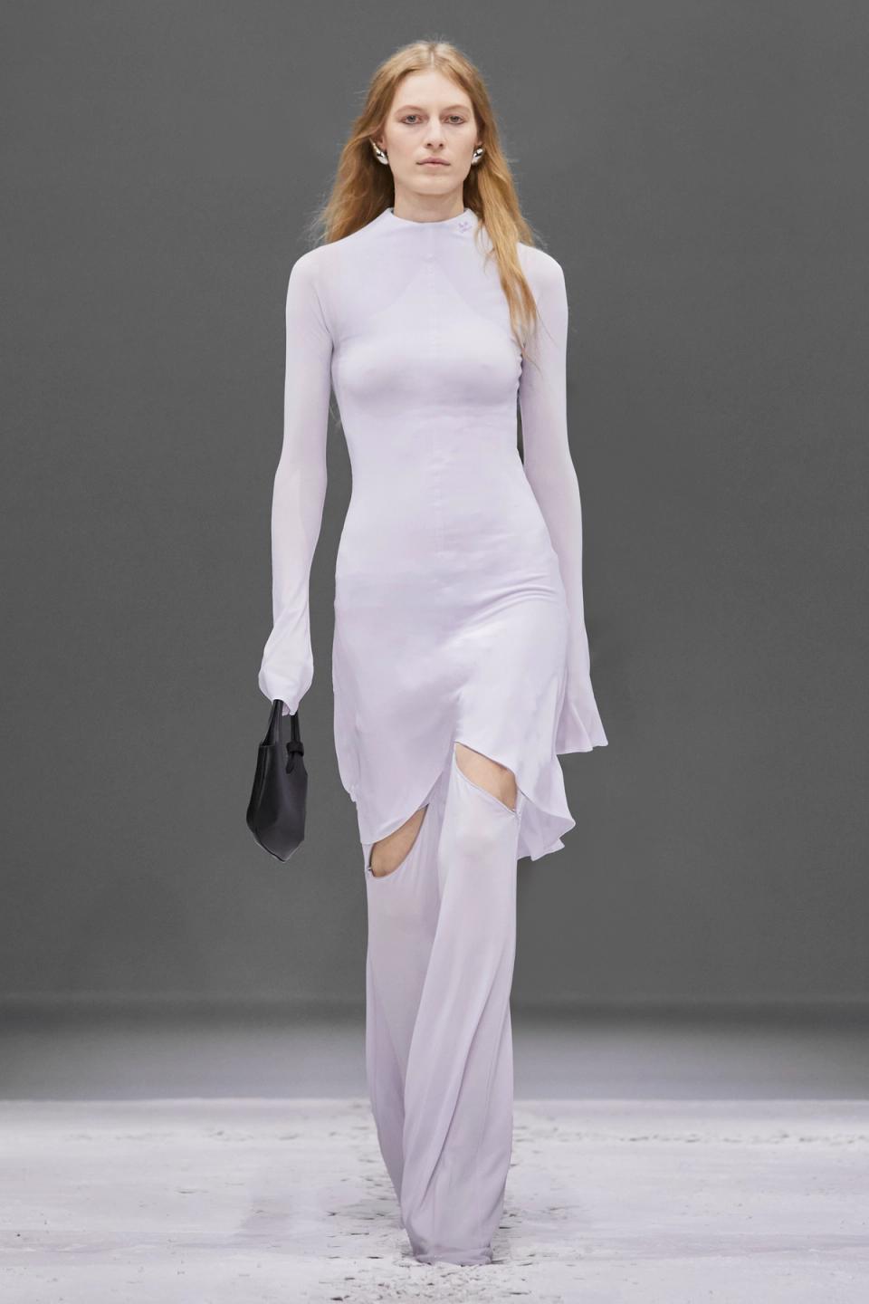 Elegant model in white Courrèges dress with cutouts, showcasing modern Parisian fashion.