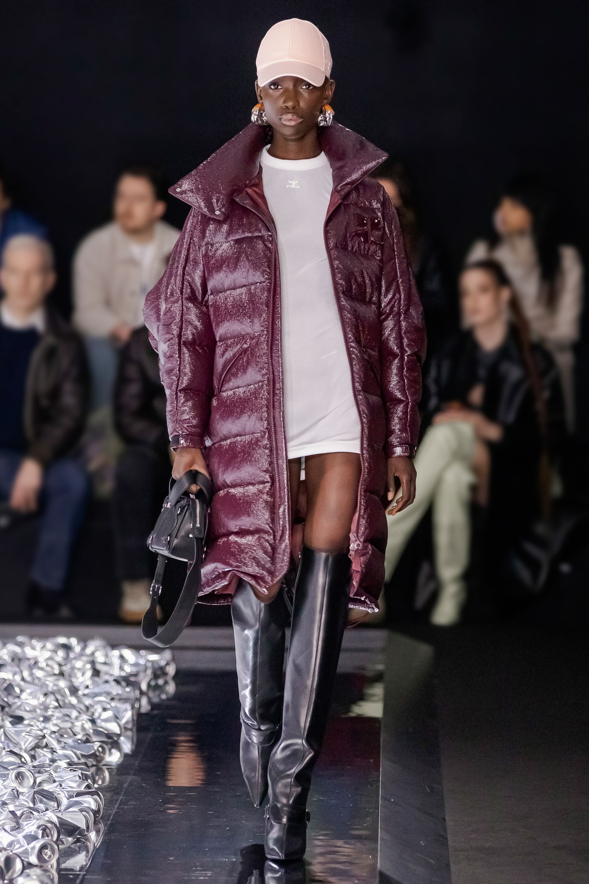 Elegant model showcasing Courrèges fashion with a shiny purple coat, white dress, and black boots.