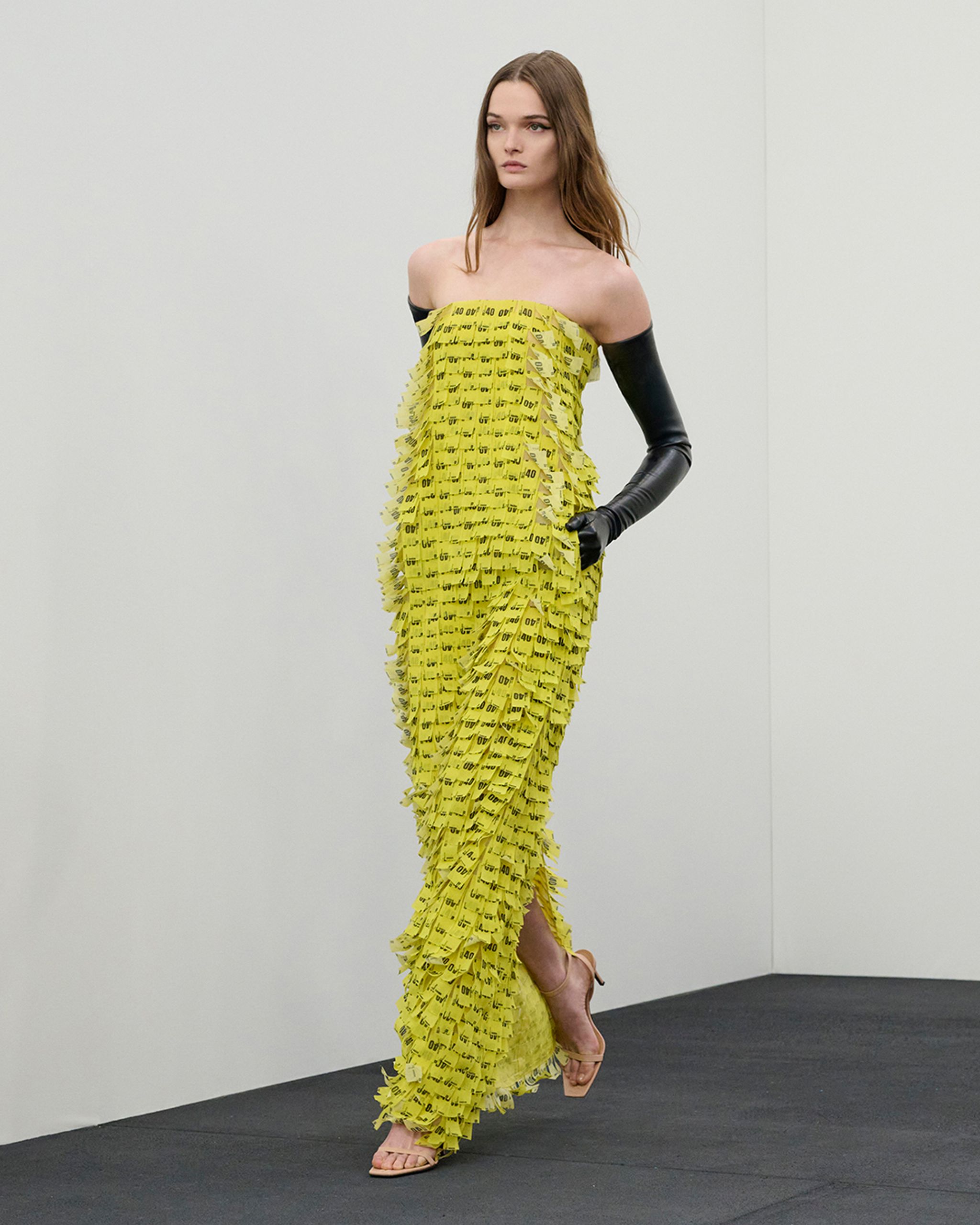 Modèle portant une robe jaune Courrèges en débris de billets pour une boutique en ligne.