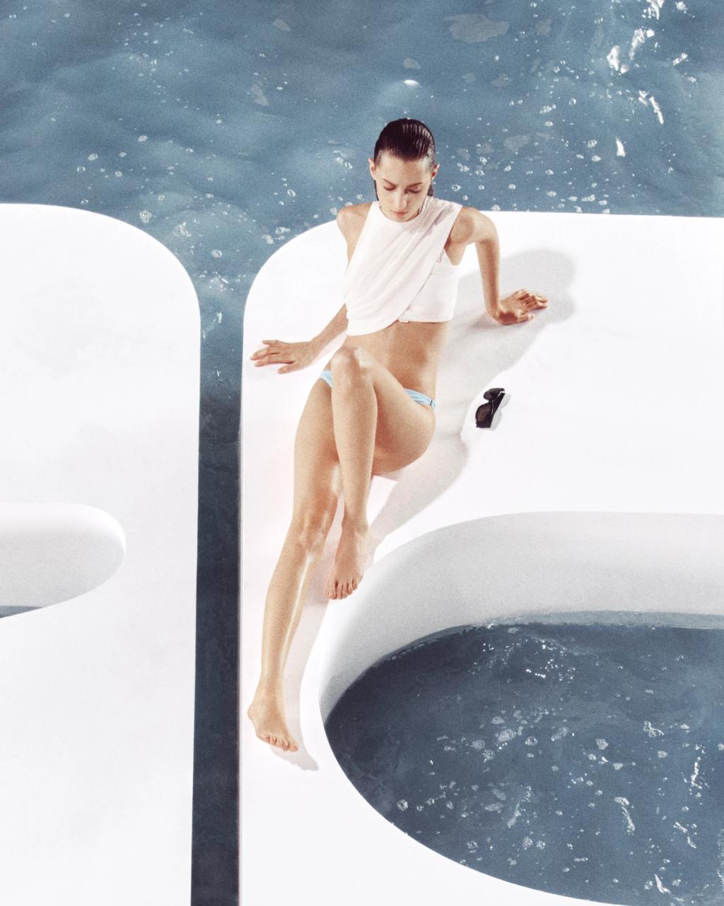 Elegant model by Courrèges in a white top and blue swimsuit, lounging on a stylish white boat.