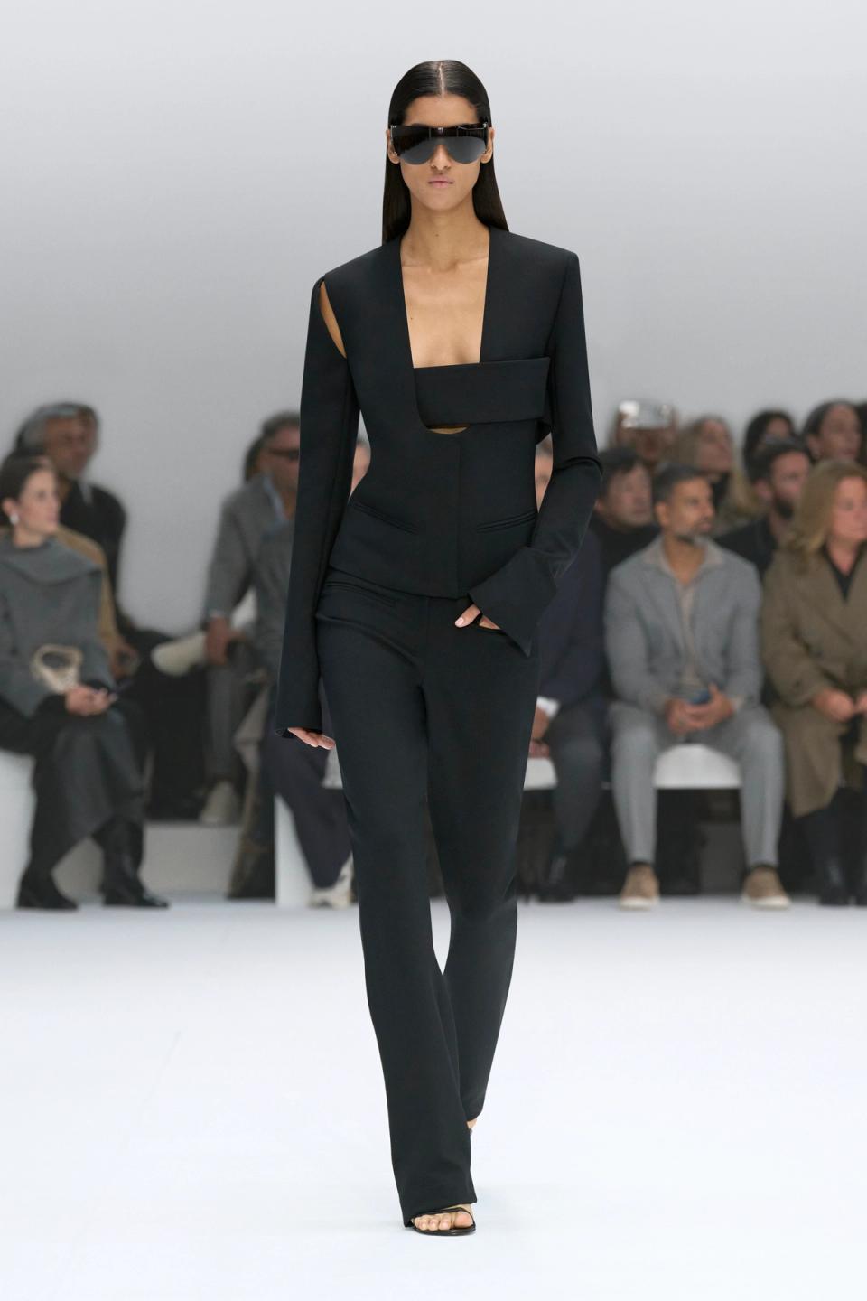 Elegant navy dress with cut-outs by Courrèges showcased on a runway at a fashion show.