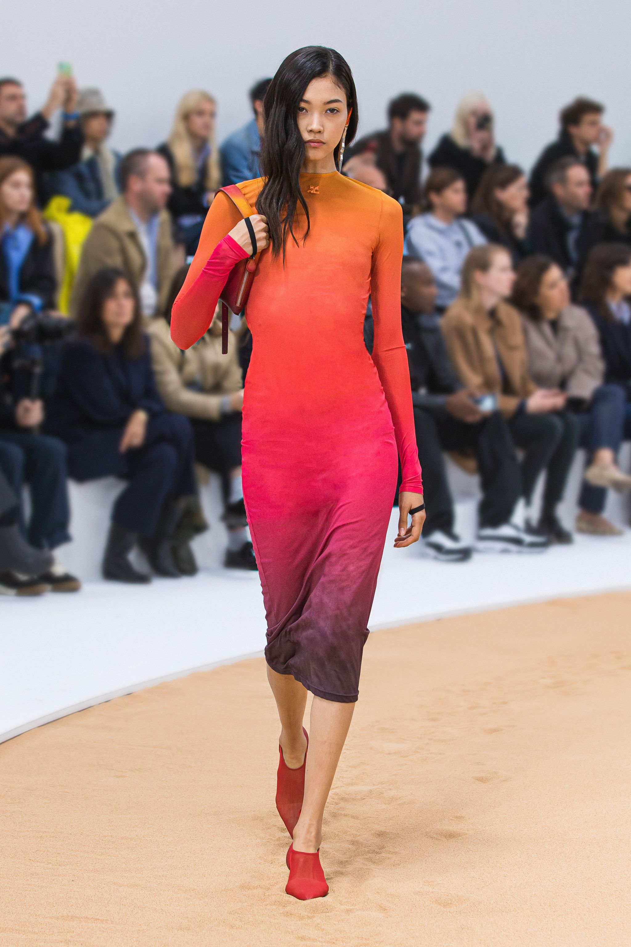 Elegant orange-to-purple gradient dress by Courrèges showcased on a runway with an audience.