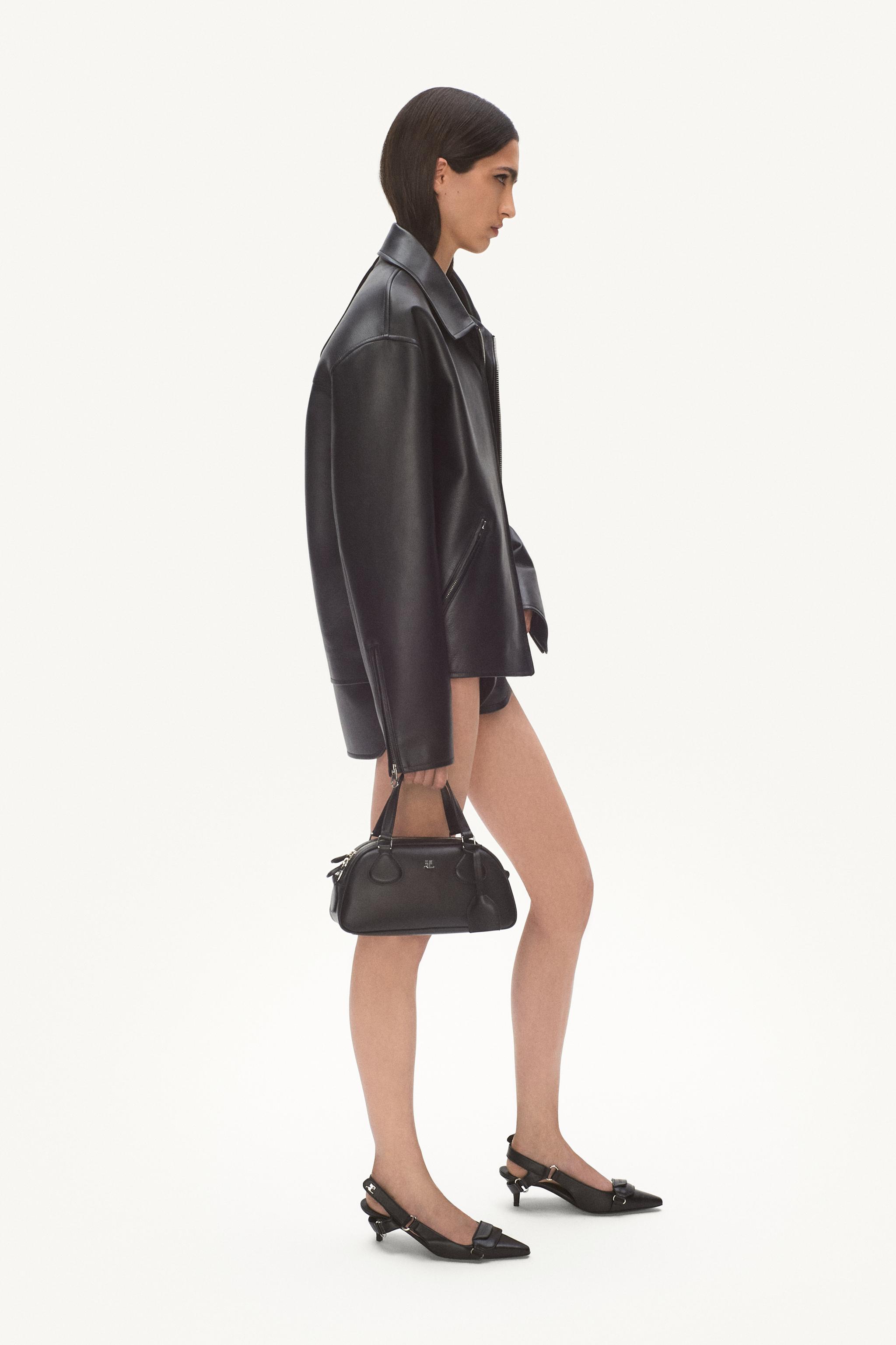 Elegant woman in black leather jacket, designer handbag, and pointed heels for Courrèges fashion.