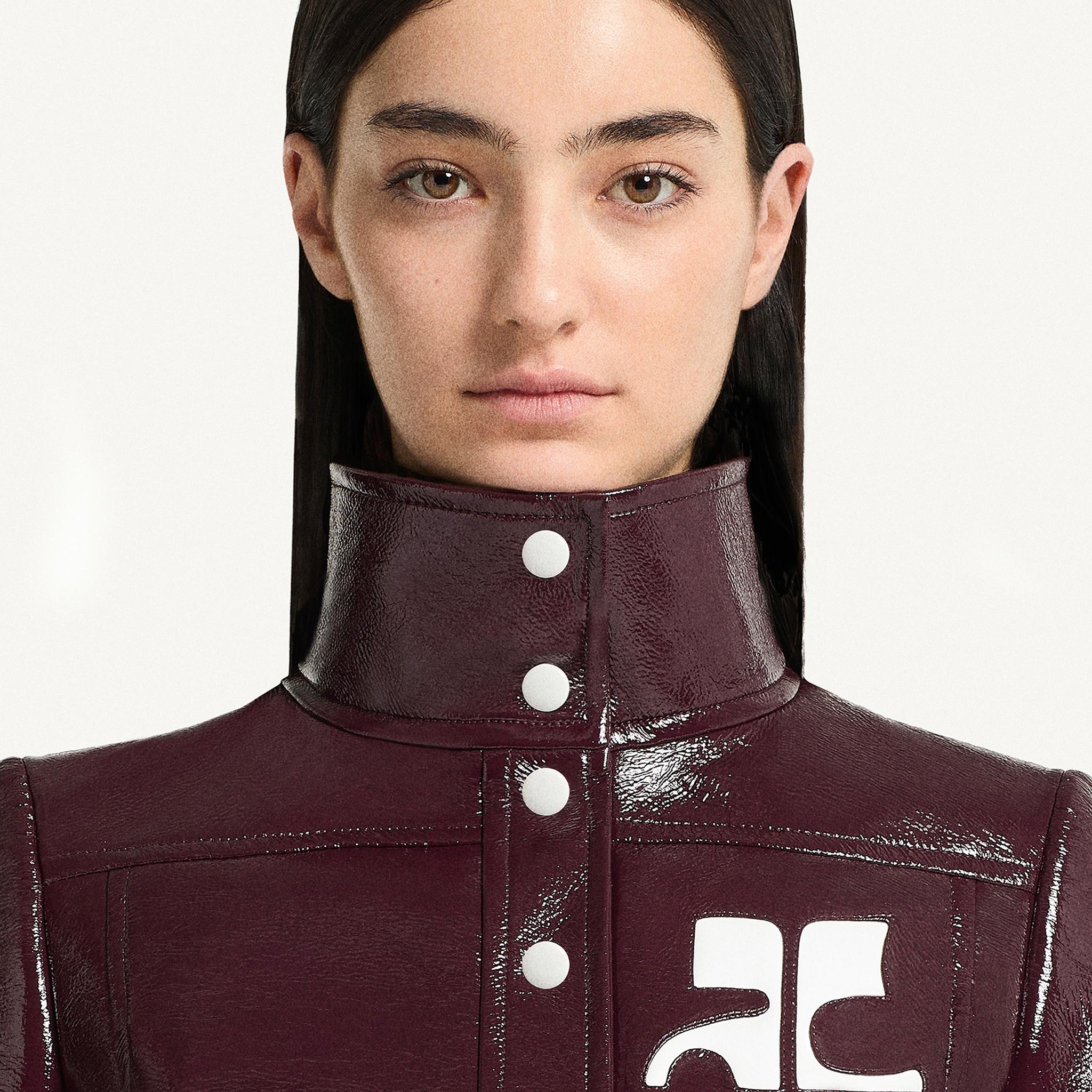 Elegant high-neck burgundy leather jacket featuring white logo details, Courrèges fashion.