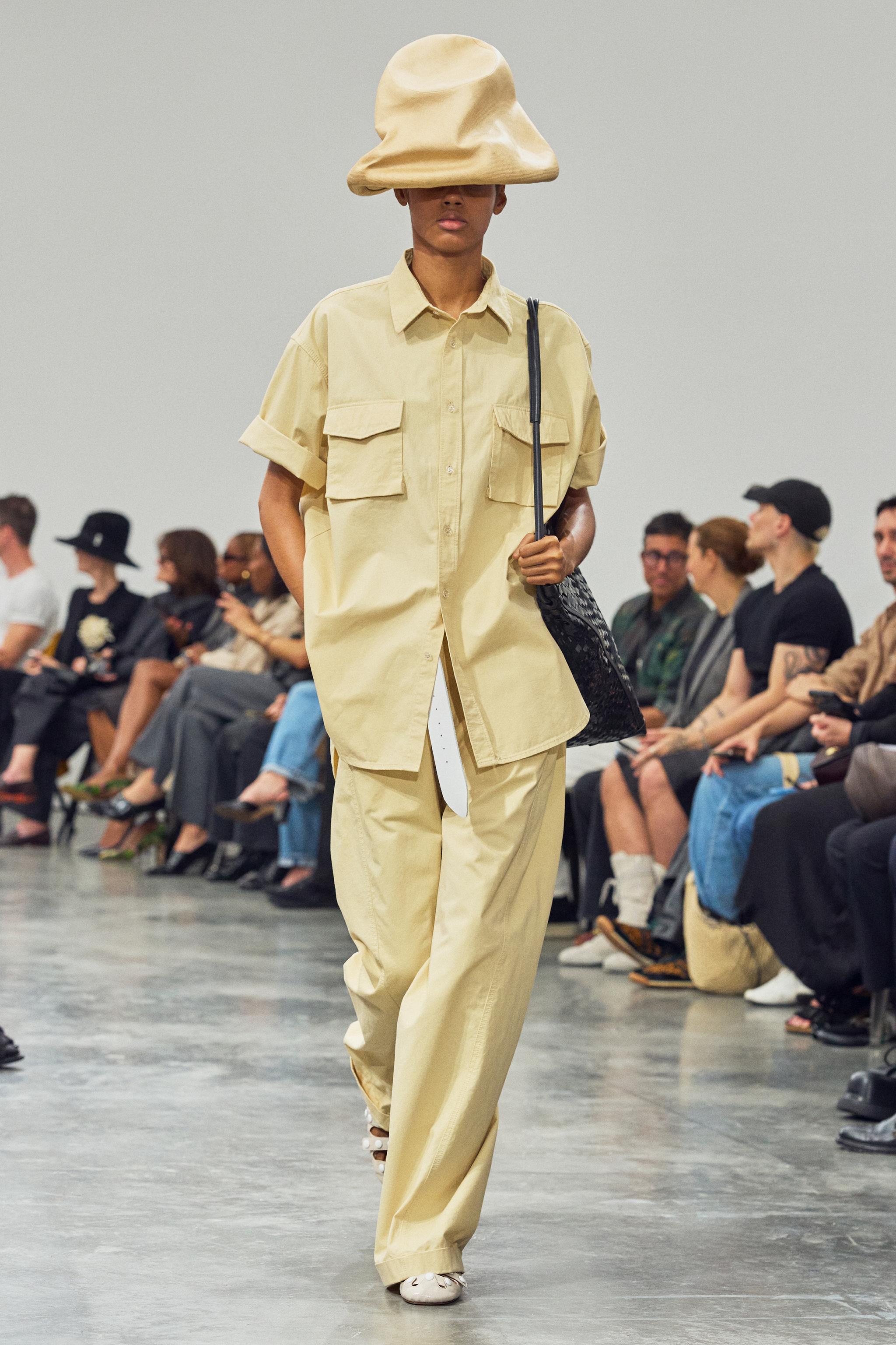 Fashion model on runway wearing beige oversized shirt and matching wide trousers, Courrèges style.