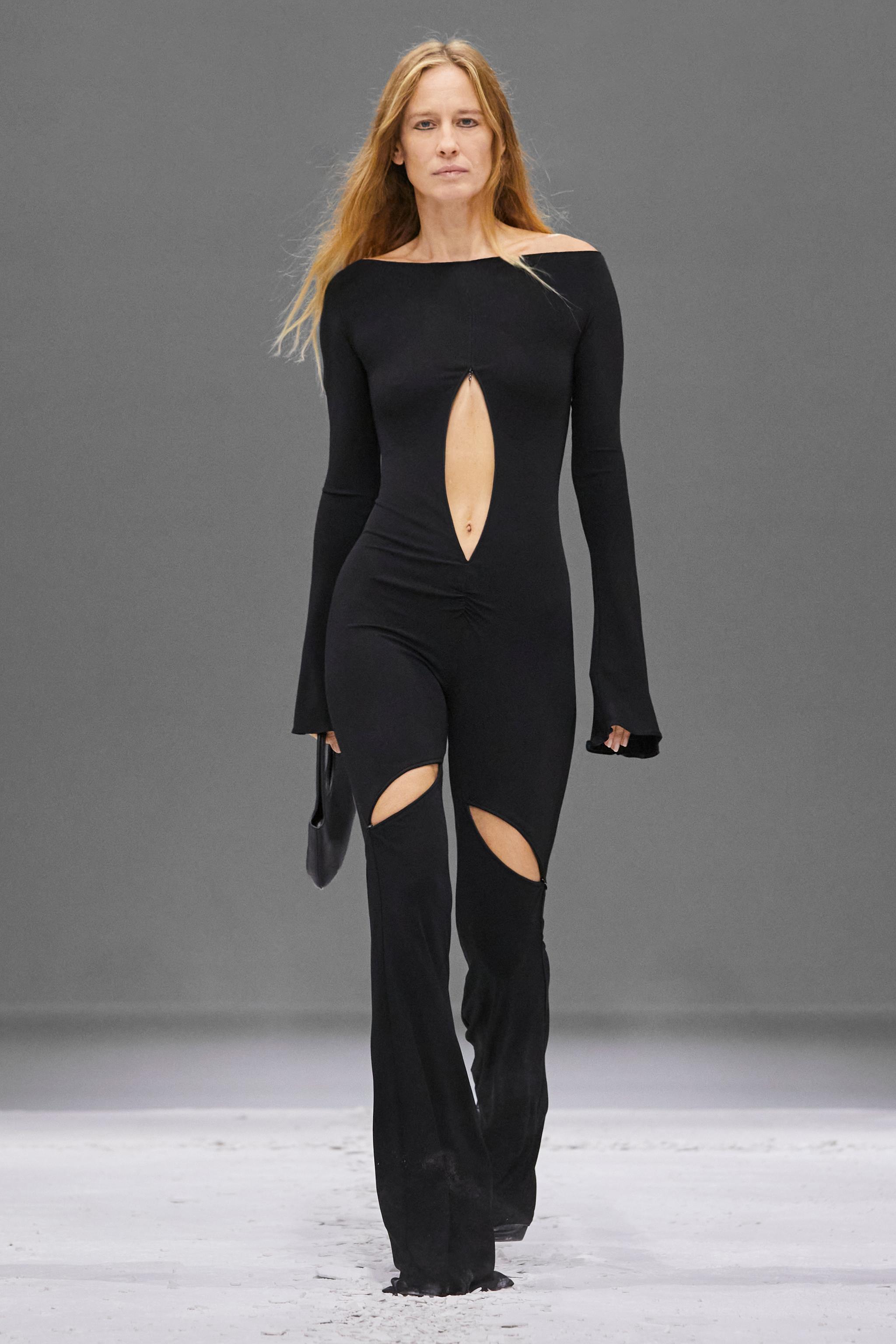 Elegant black jumpsuit with cutouts, model walking on runway for Courrèges fashion brand.