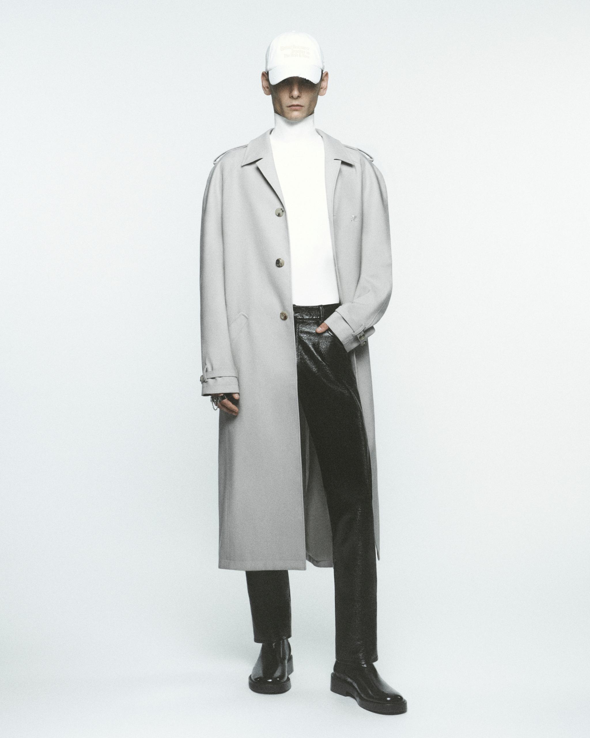 Elegant model wearing Courrèges fashion outfit, featuring a long trench coat, turtleneck, and stylish accessories.