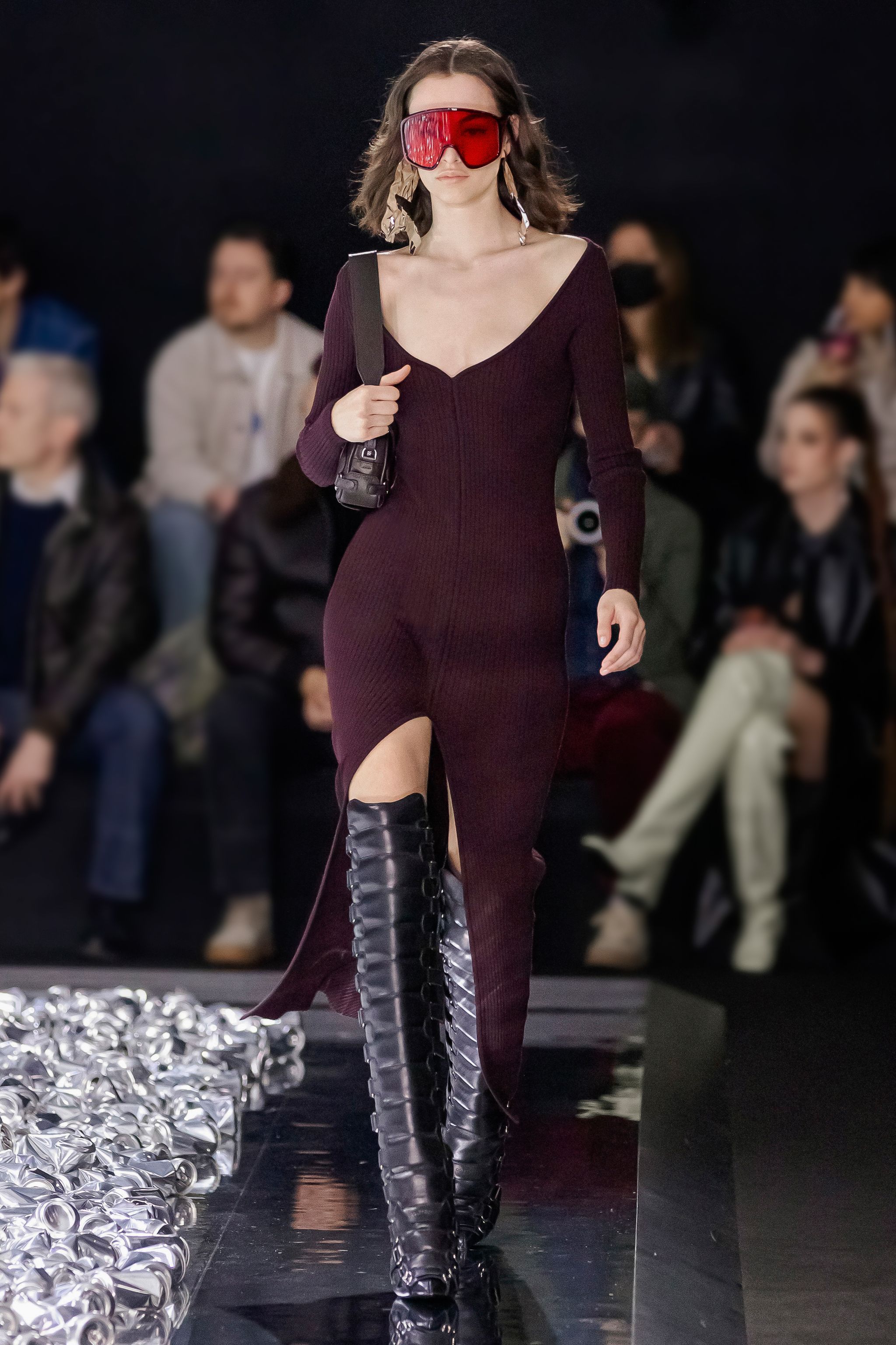 Elegant model walking runway in a fitted deep burgundy dress with thigh-high lace-up boots for Courrèges.