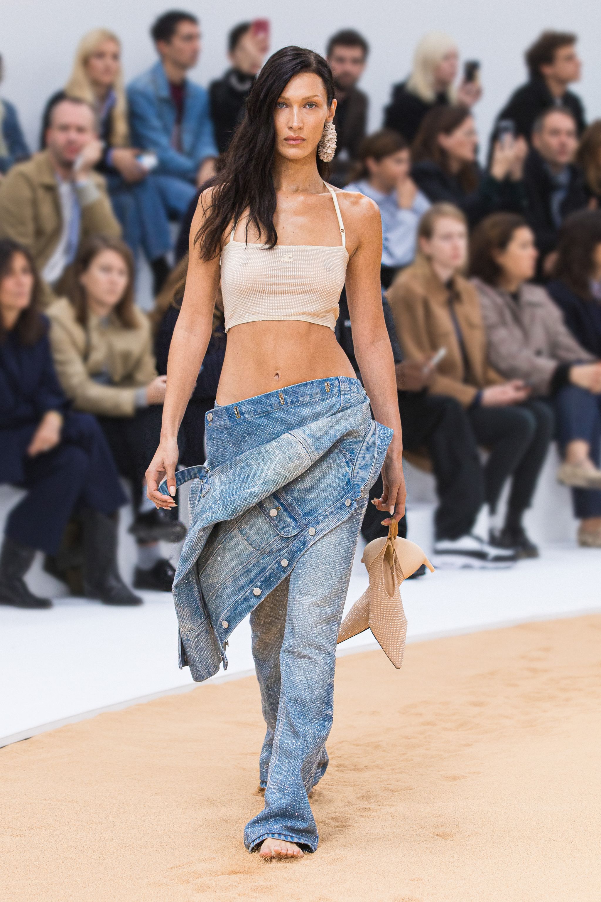 Elegant model showcases Courrèges' contemporary fashion on runway with denim and neutral tones.
