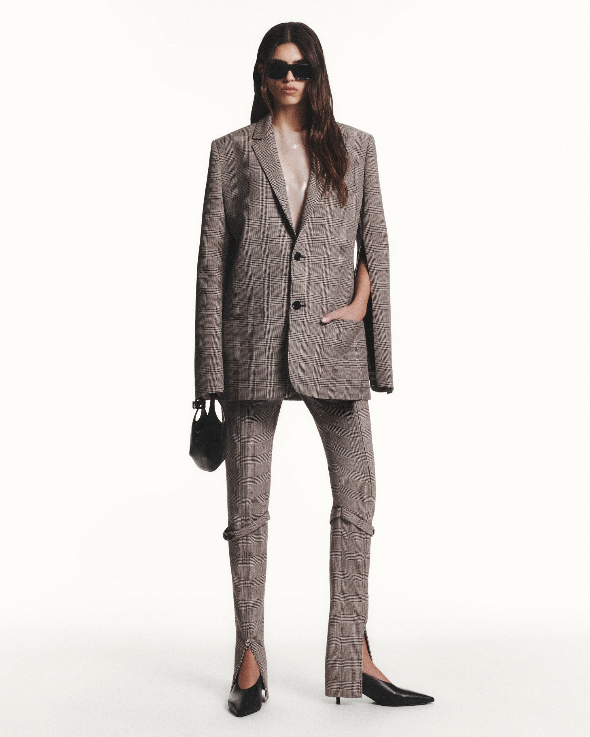 Elegant model wearing Courrèges checked suit with black sunglasses, in a fashion shoot.