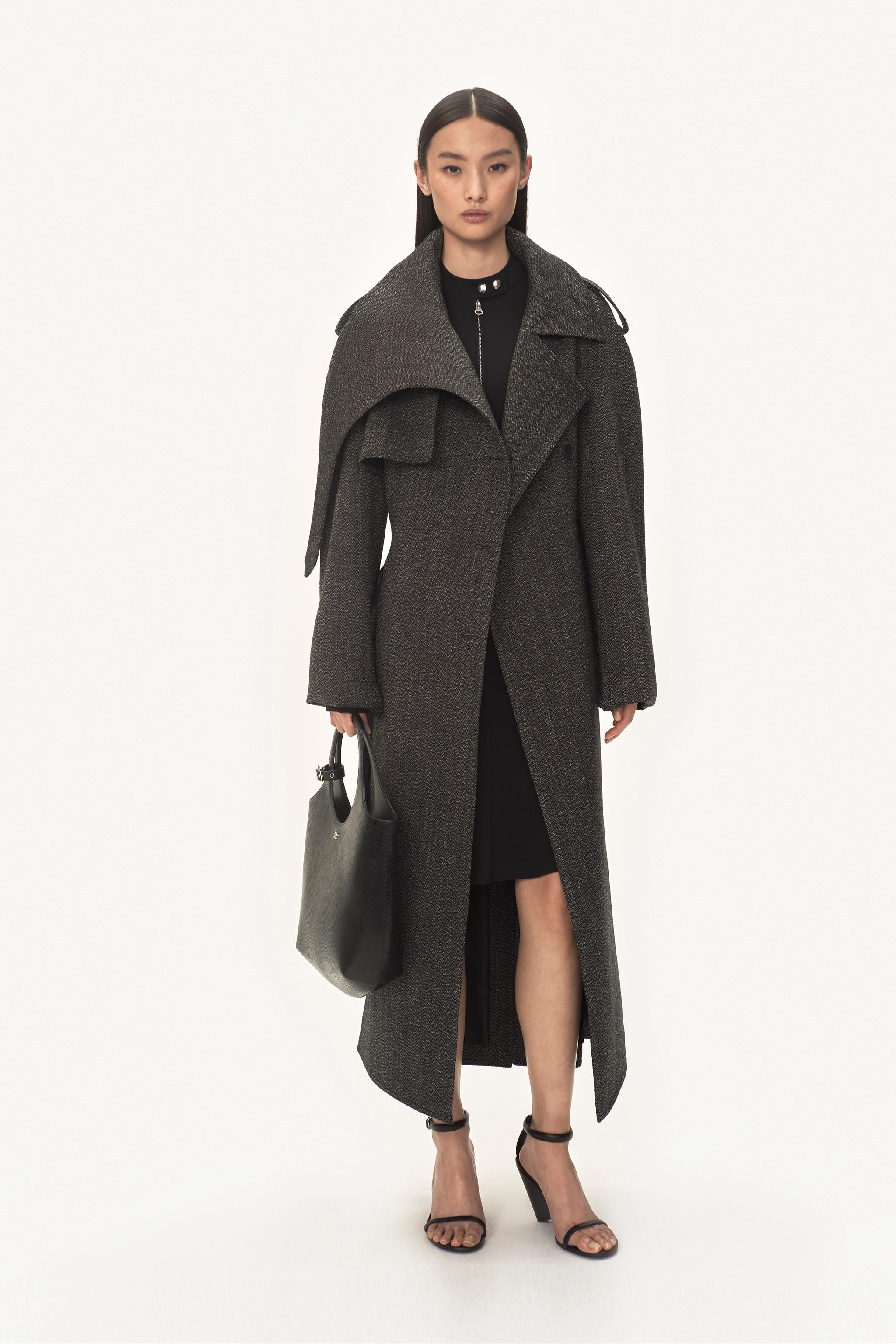 Robe noire élégante avec un long manteau texturé et talons chics, représentant la mode Courrèges.