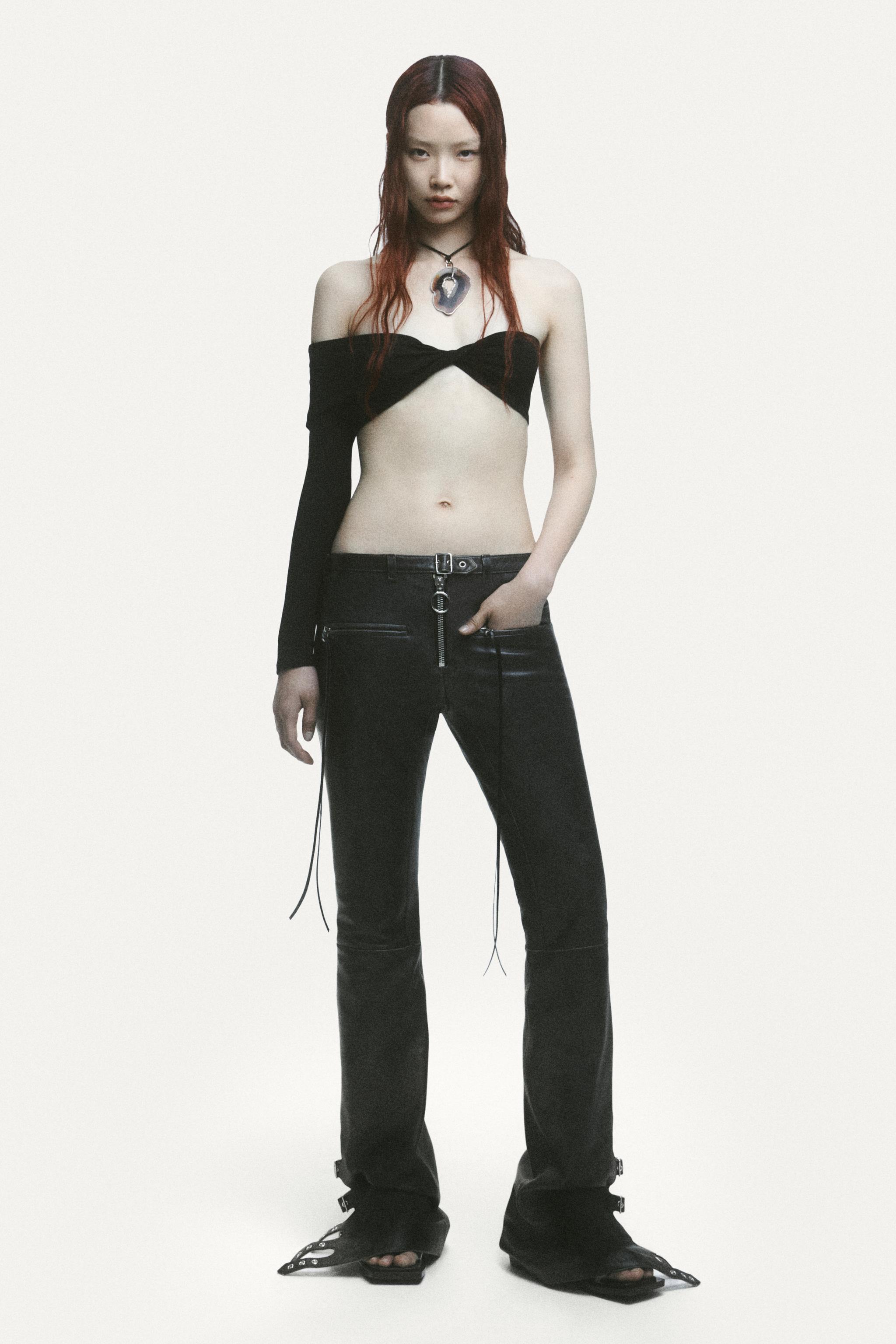 Elegant fashion model in a Courrèges outfit with black pants and a stylish off-shoulder top.