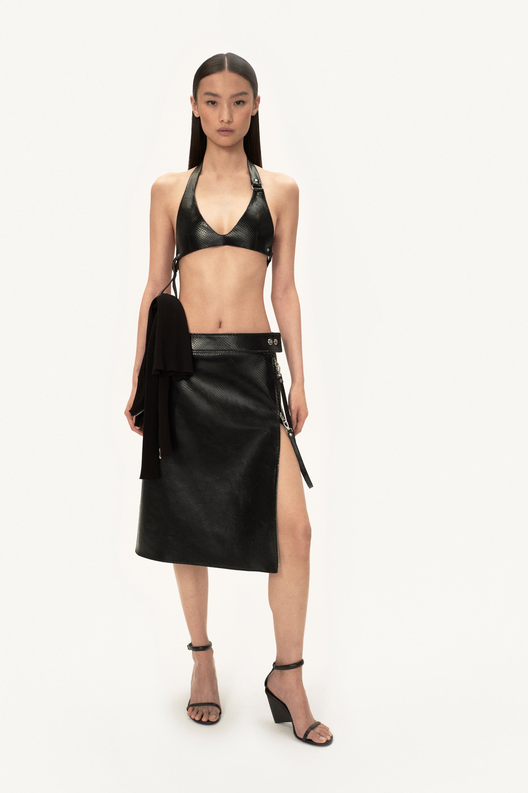 Ensemble de mode élégant en cuir noir de Courrèges, avec top court et jupe midi à fente.