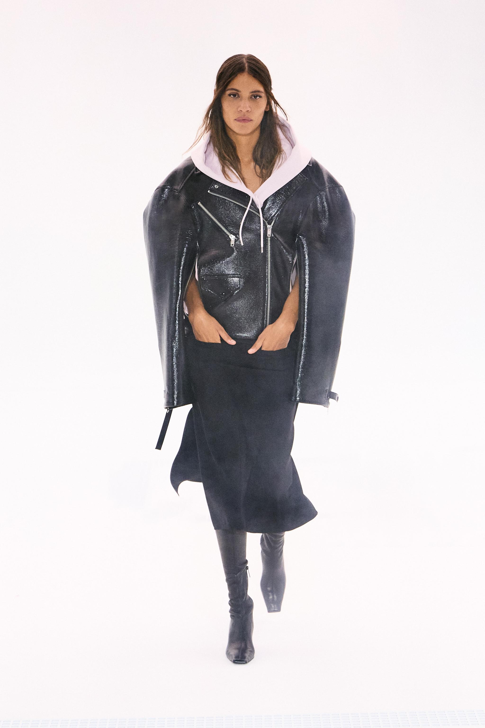 Model in black leather jacket, oversized with a white hoodie, on a runway for Courrèges.