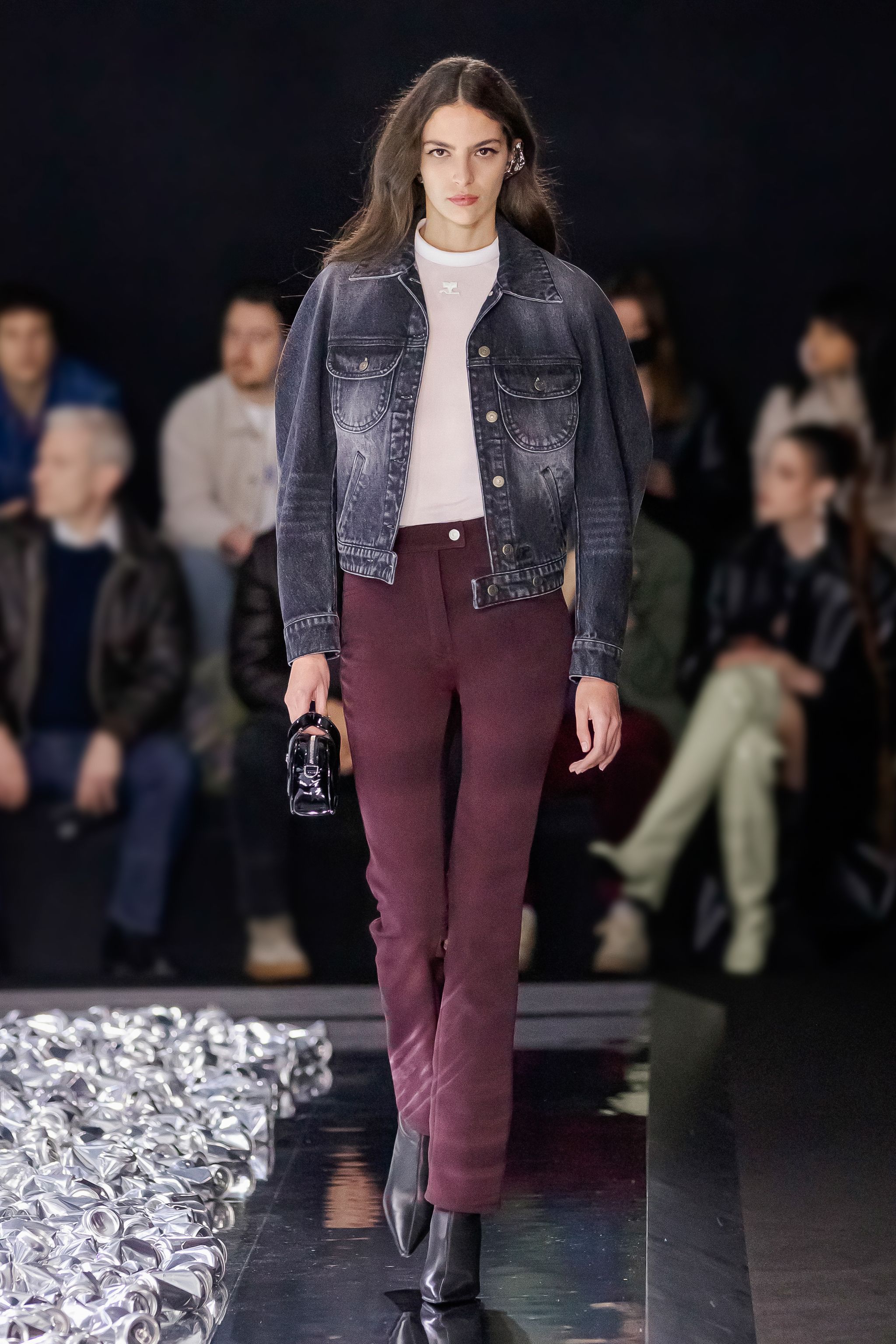 Elegant model in denim jacket and burgundy pants on a fashion runway for Courrèges.