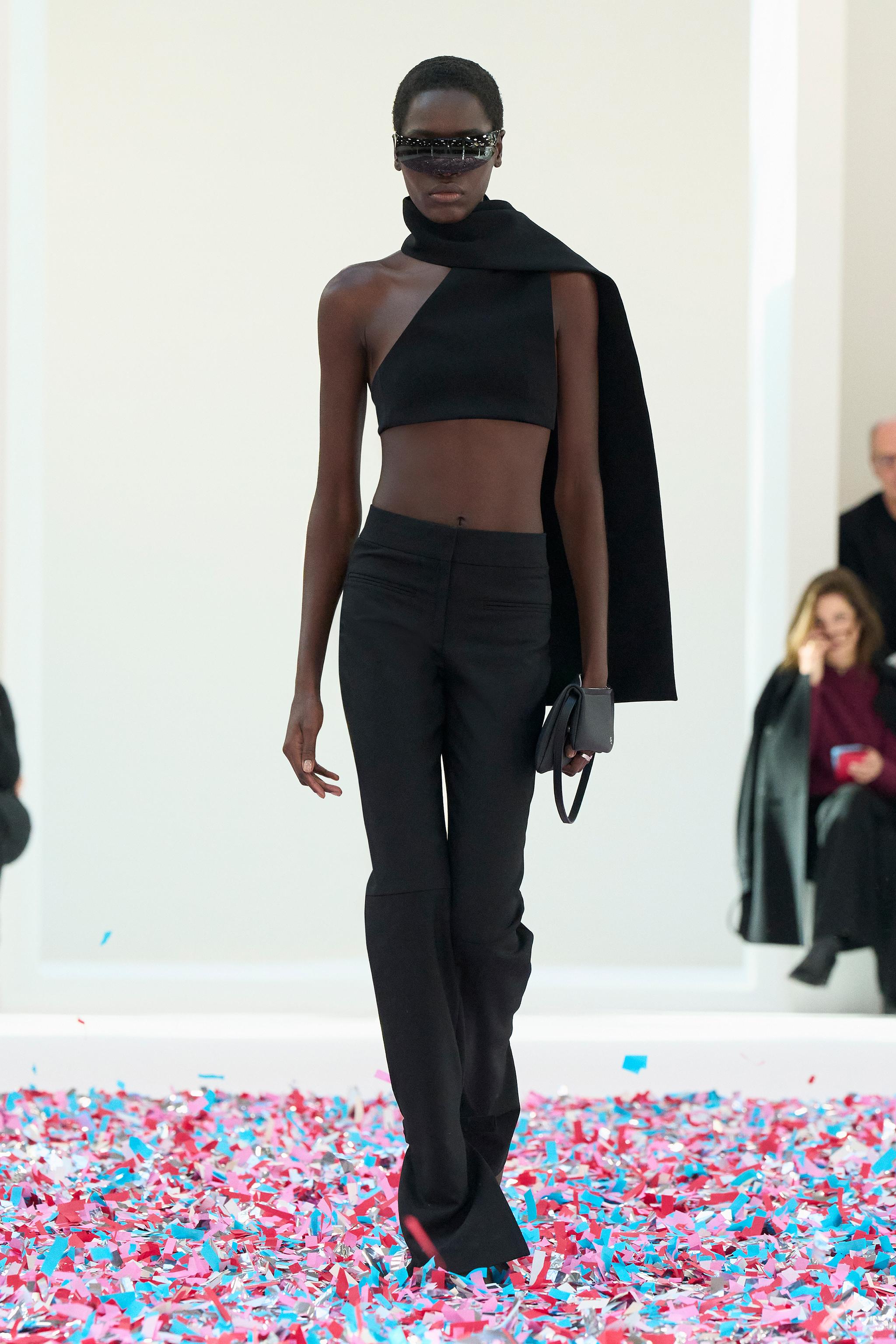 Elegant black high-fashion model wearing Courrèges outfit on runway with colorful confetti.